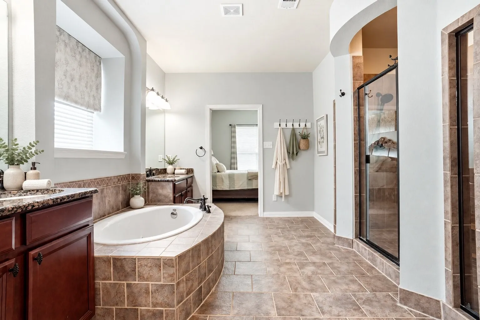 Primary bathroom featuring a large soaking tub, dual vanities with granite countertops, a separate walk-in shower with dual shower heads, and two separate closets. Photos have been AI enhanced for presentation; no material property features were altered.