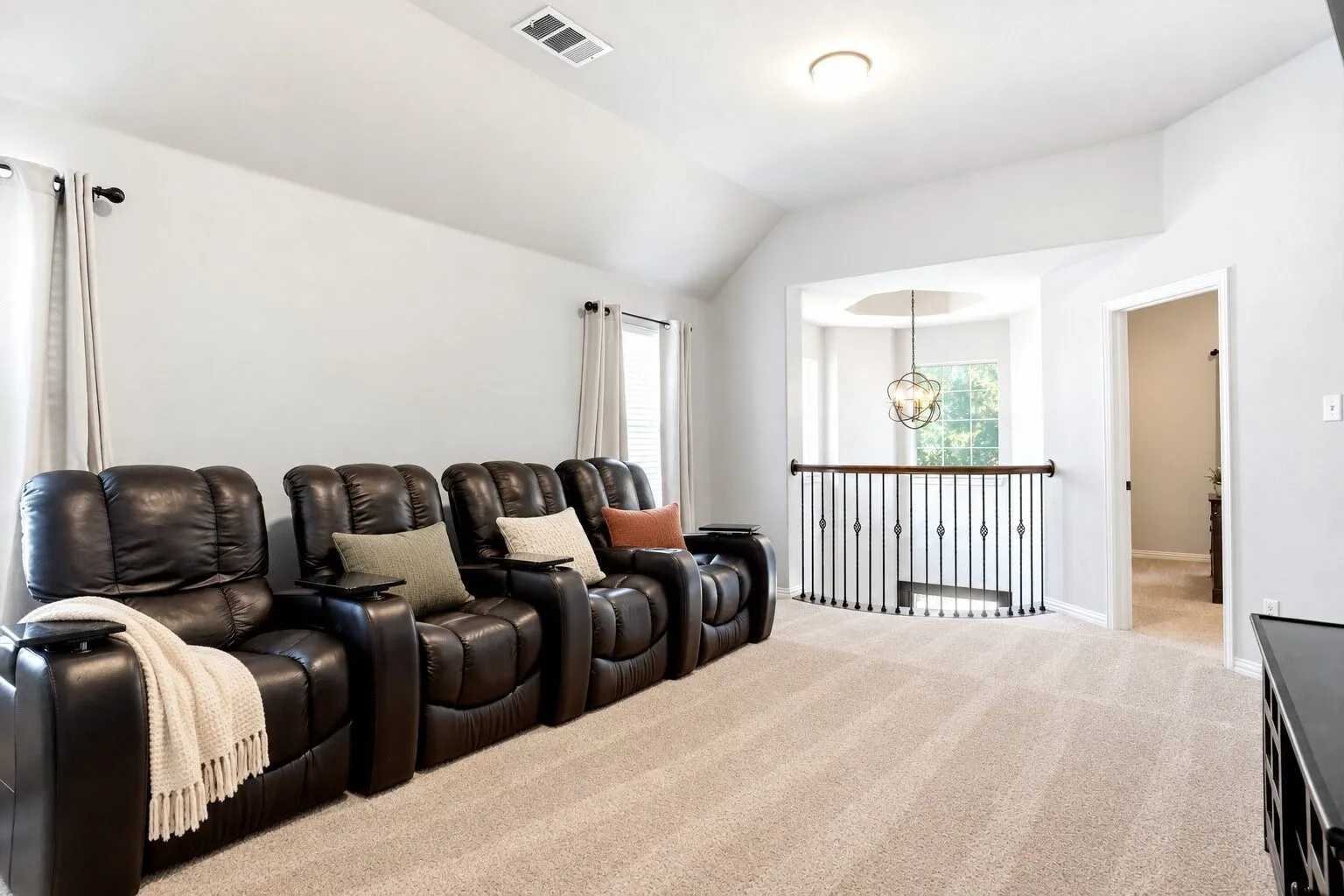 Spacious upstairs media room featuring vaulted ceilings, abundant natural light, and plenty of space for theater-style seating and entertainment. Photos have been AI enhanced for presentation; no material property features were altered.