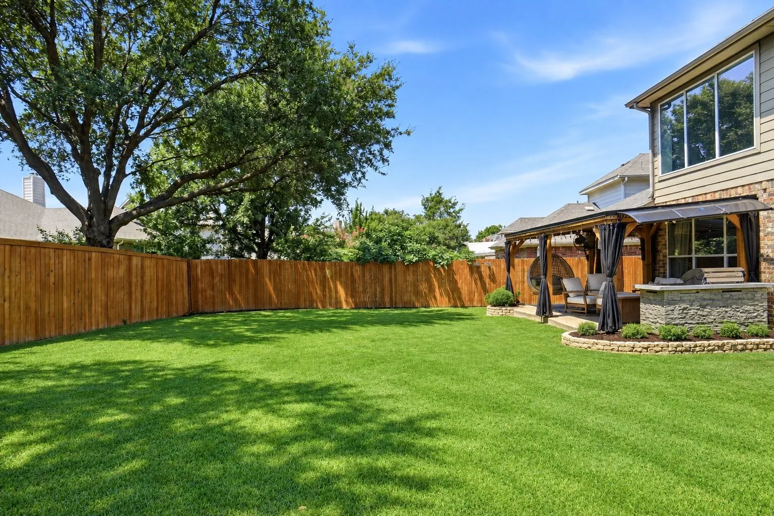 Large, fully fenced backyard offering plenty of open lawn space, mature shade trees, and room for play, pets, or outdoor activities. Photos have been AI enhanced for presentation; no material property features were altered.