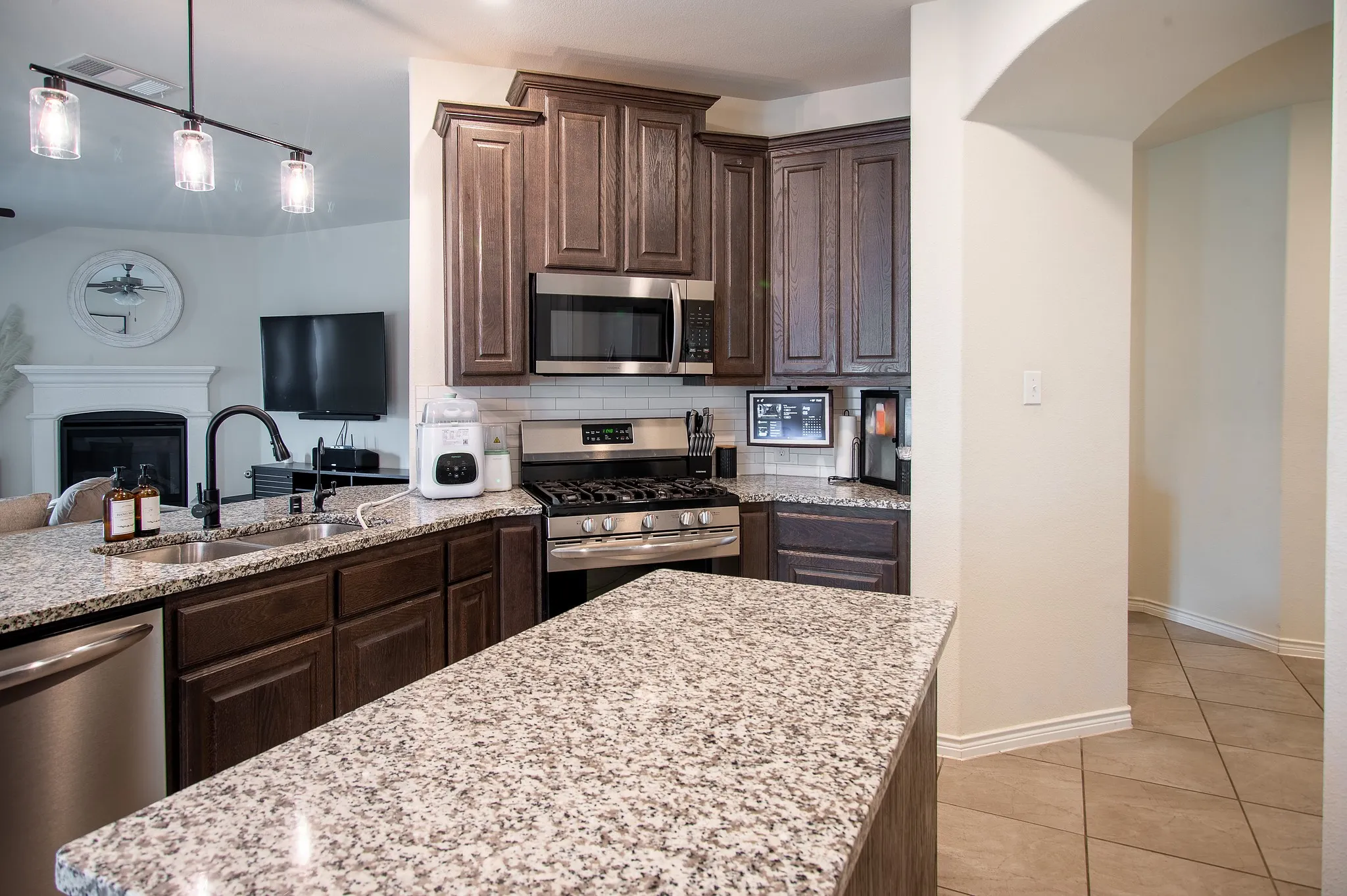 Kitchen featuring dark wood cabinetry, granite countertops, stainless steel appliances, and a tile backsplash