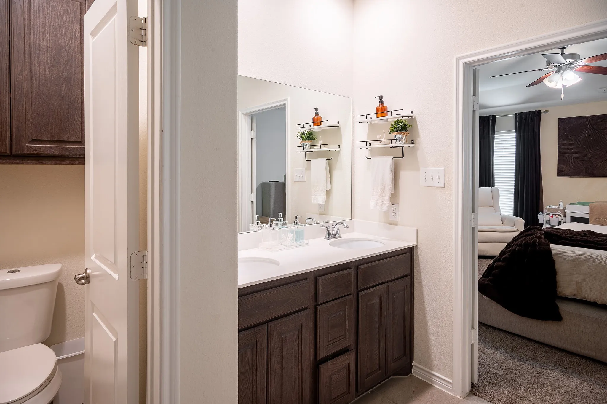 Spa-inspired master bath featuring a dual-sink vanity with wood-finish cabinetry, white quartz countertops, and polished chrome fixtures