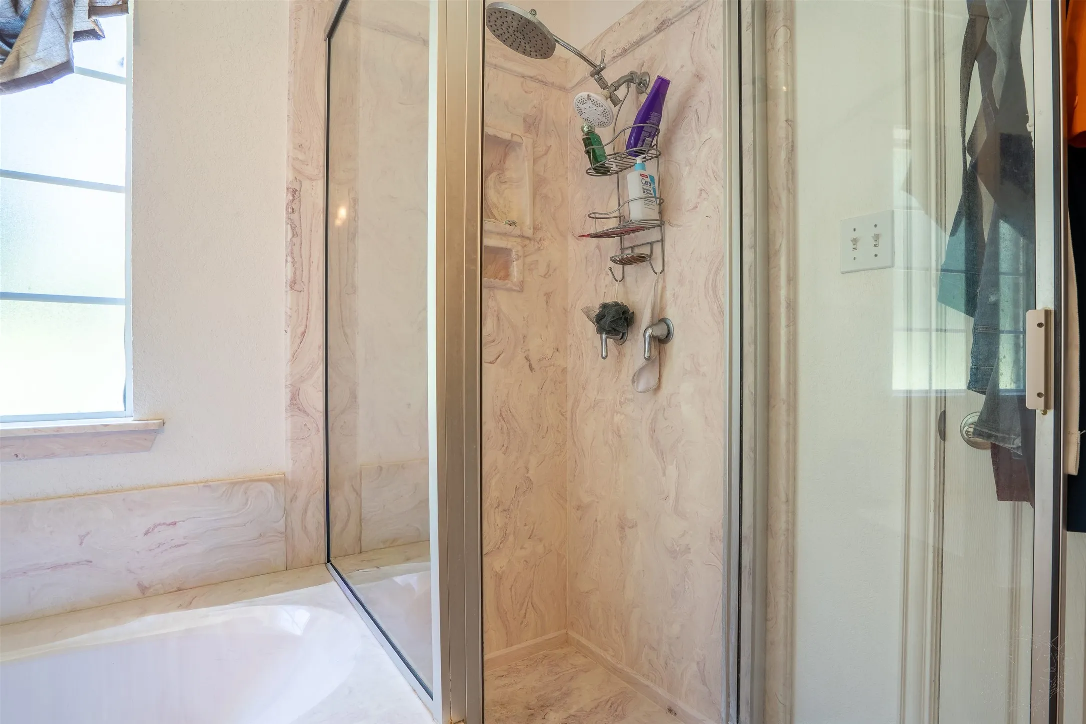 Glass-enclosed shower with a rainfall integrated shelf, and stone-finish surround