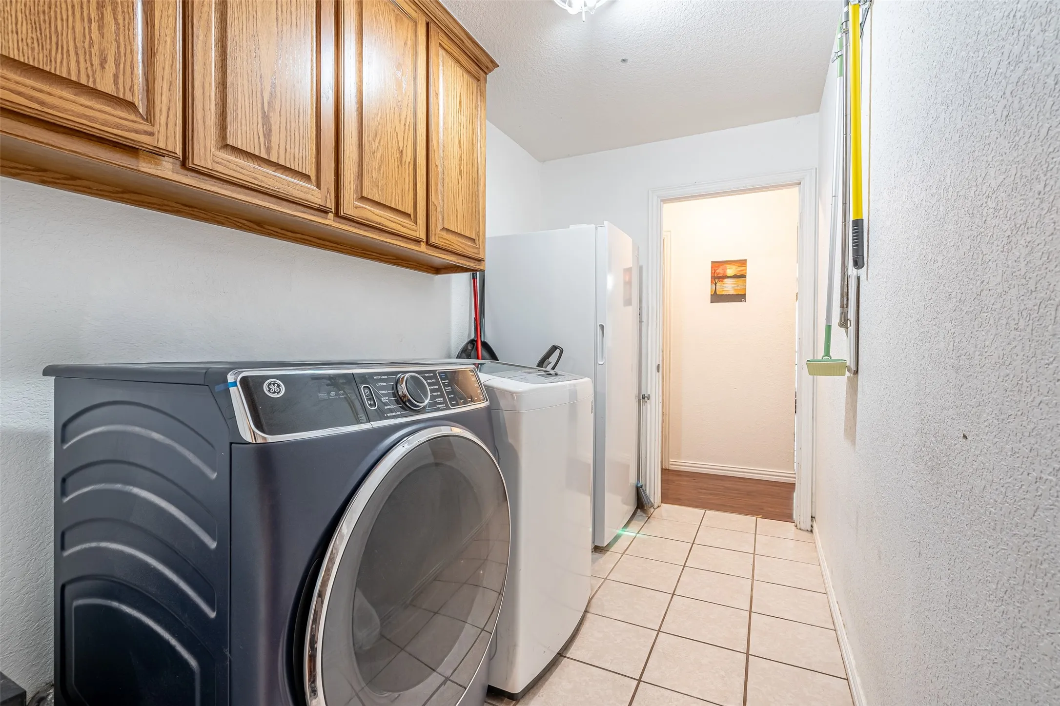 Utility area featuring overhead wood cabinetry and tile flooring