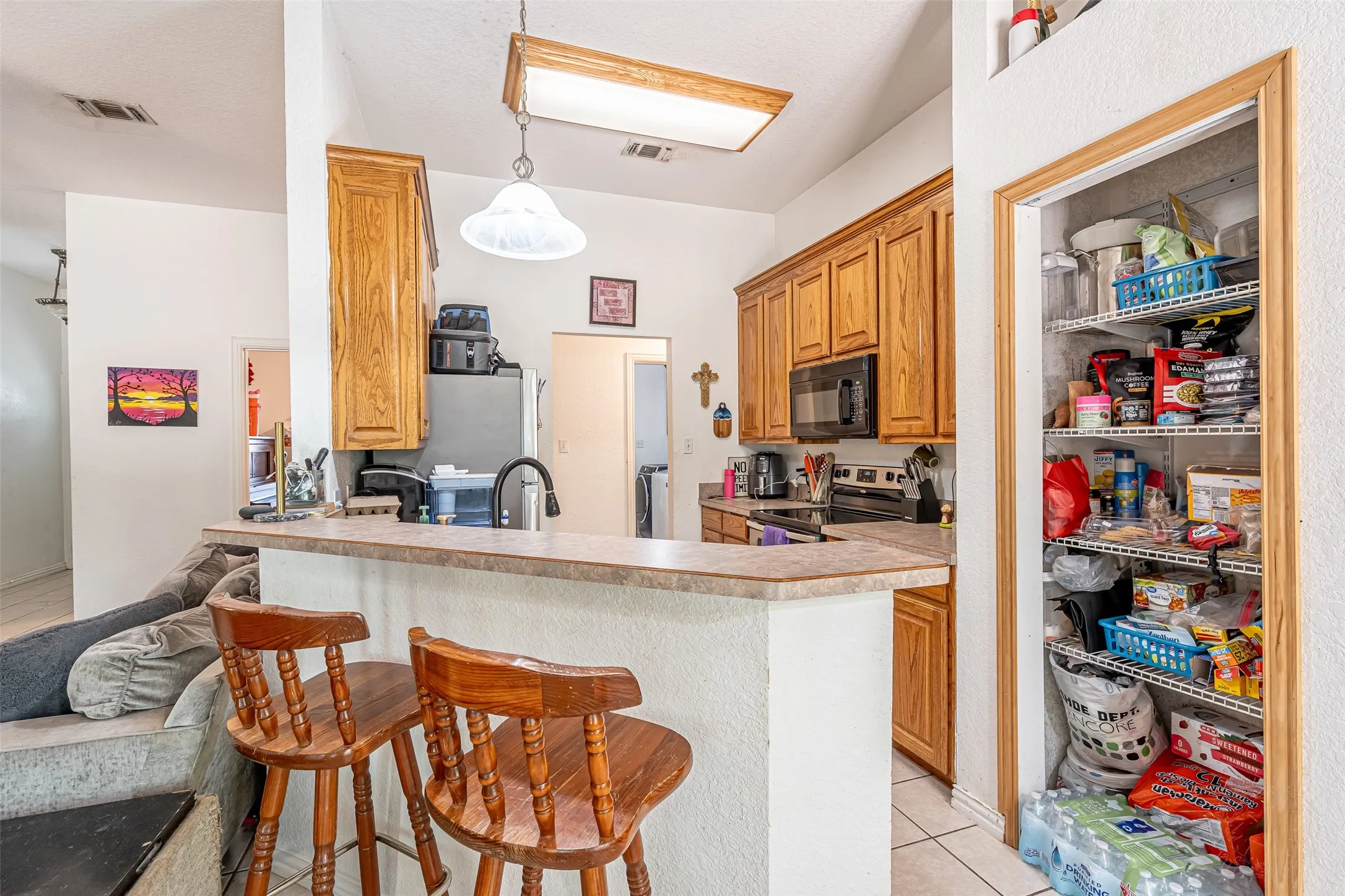 Kitchen featuring wood cabinetry, dark countertops, a breakfast bar, and stainless steel appliances