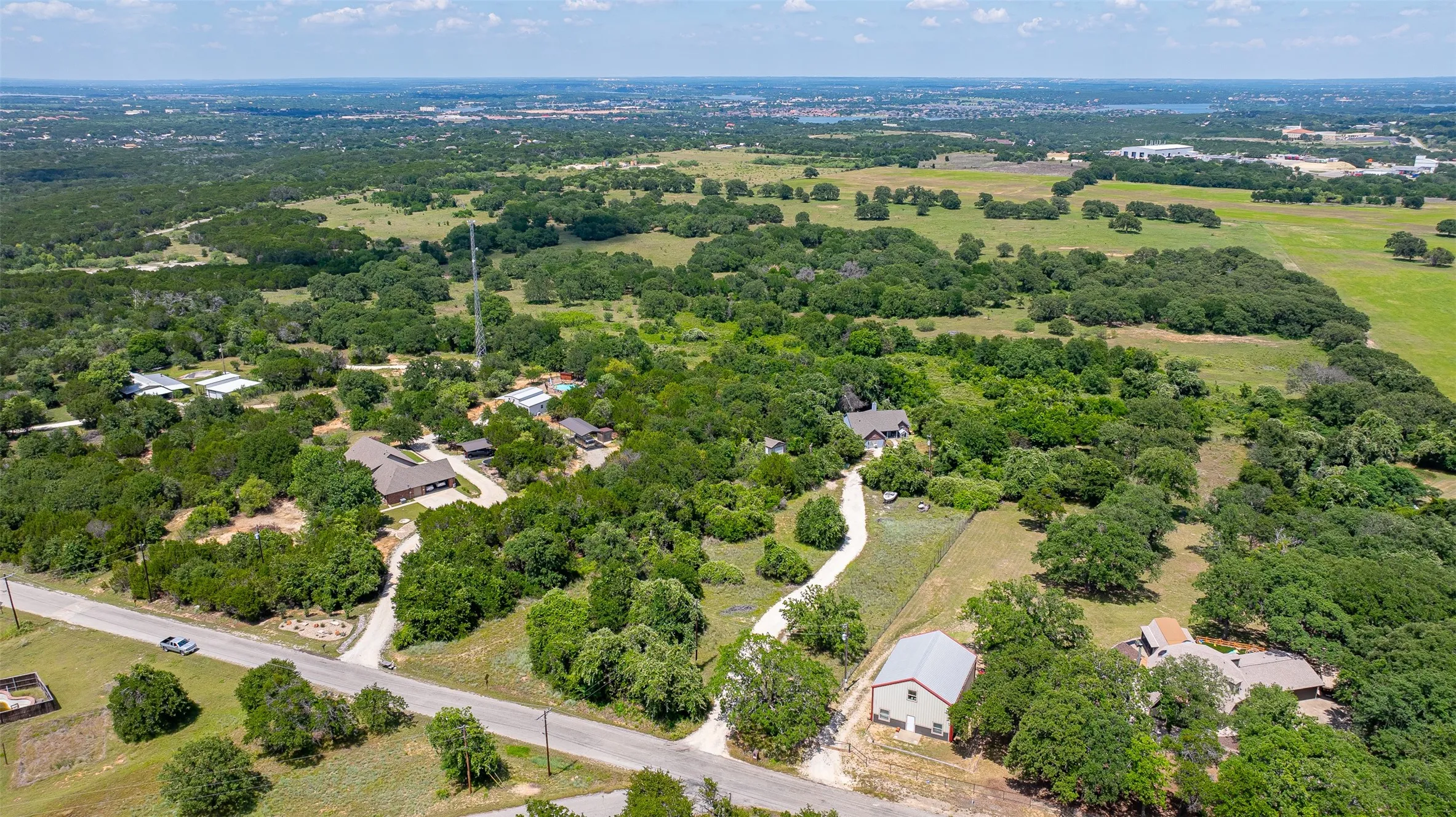 Expansive property featuring abundant mature trees, a private driveway, and multiple residential structures