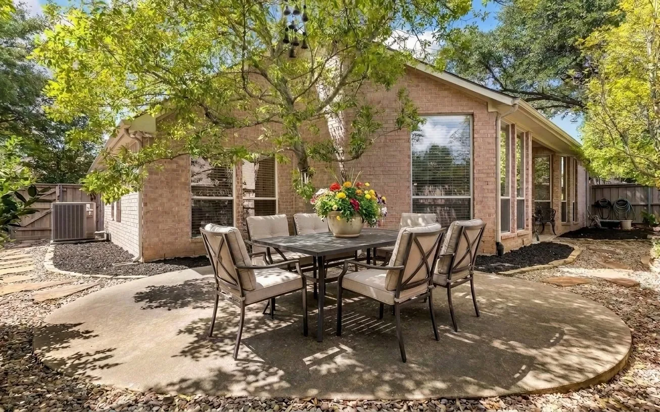 Brick exterior with large windows, mature trees, and an air conditioning unit