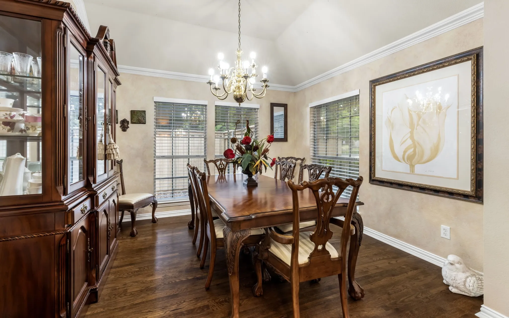Vaulted ceiling with a chandelier, wood-finish flooring, and multiple windows with blinds