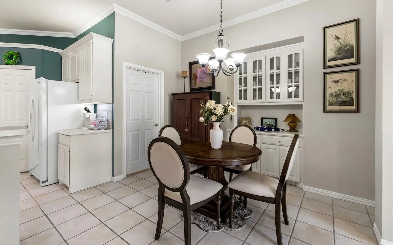 Kitchen and dining area featuring tile flooring, white cabinetry, integrated glass-front display cabinet, and a built-in buffet