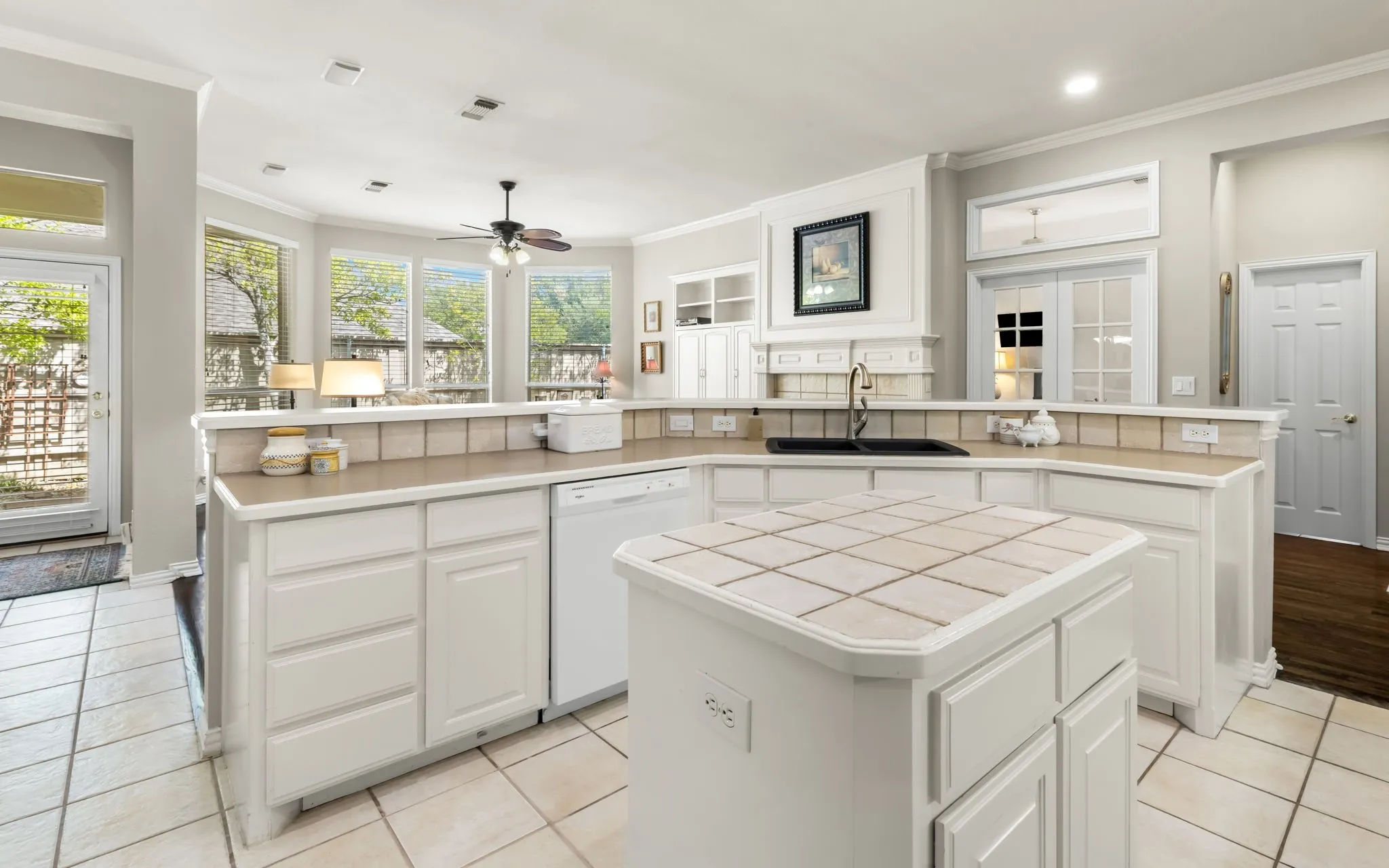 White cabinetry with tile countertops, integrated dishwasher, tile flooring, and a central island with a tile surface