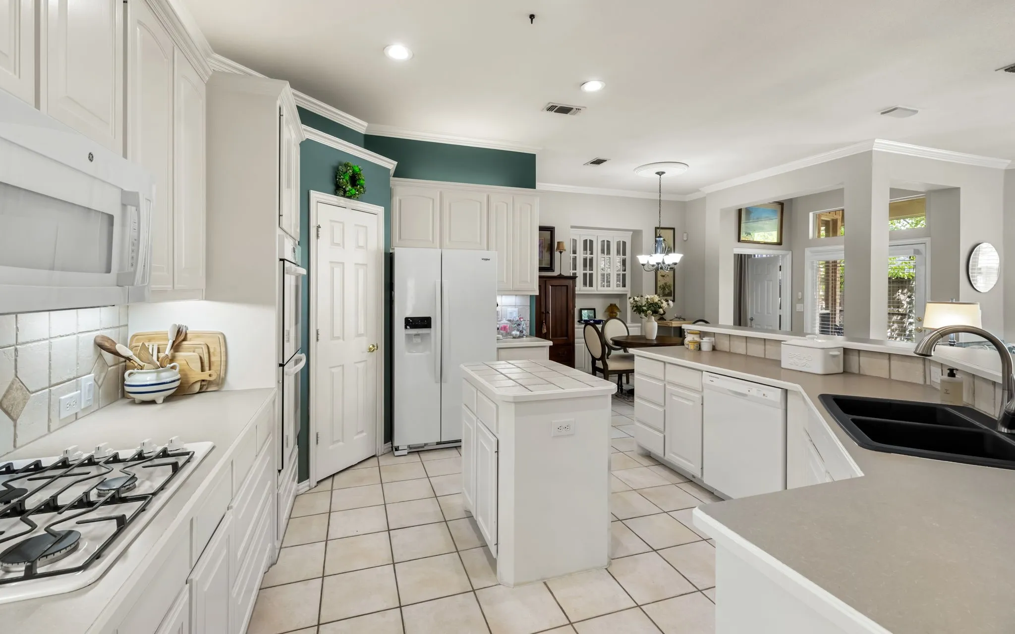 White cabinetry with crown molding, integrated appliances, and a central island