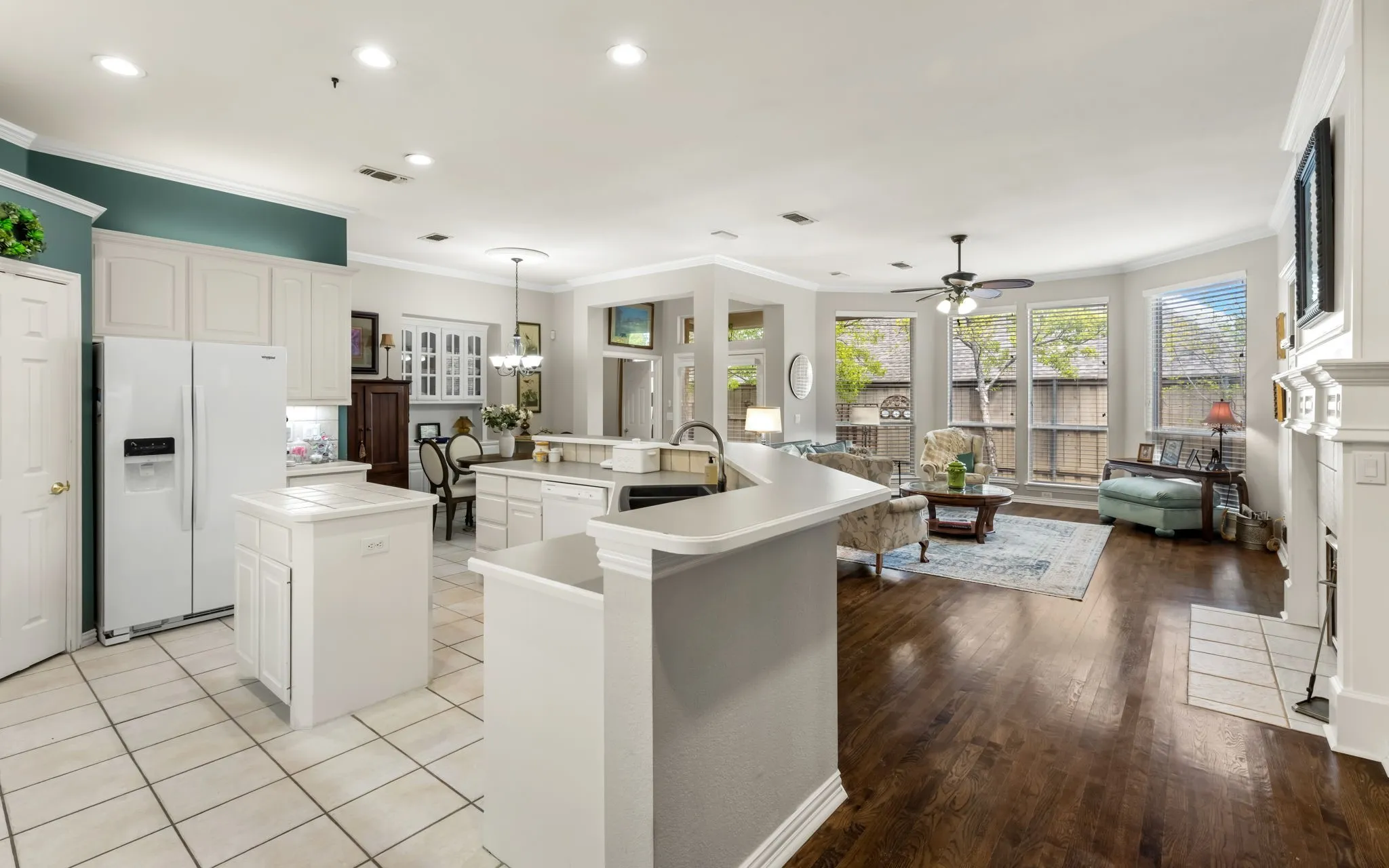White cabinetry, tile flooring, wood-finish flooring, recessed lighting, and a built-in fireplace
