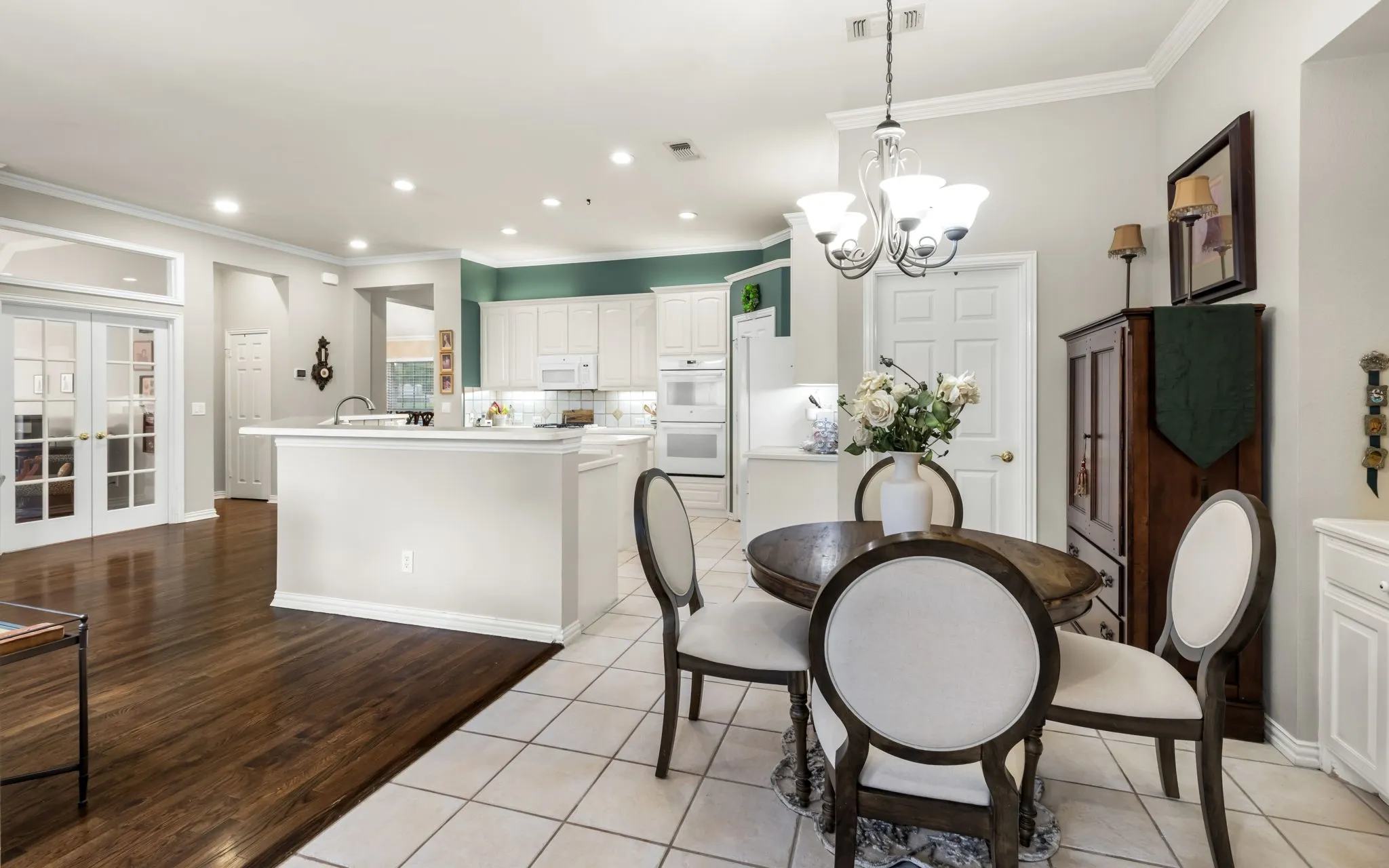 Kitchen featuring white cabinetry, white appliances, a center island with a sink, and tile flooring