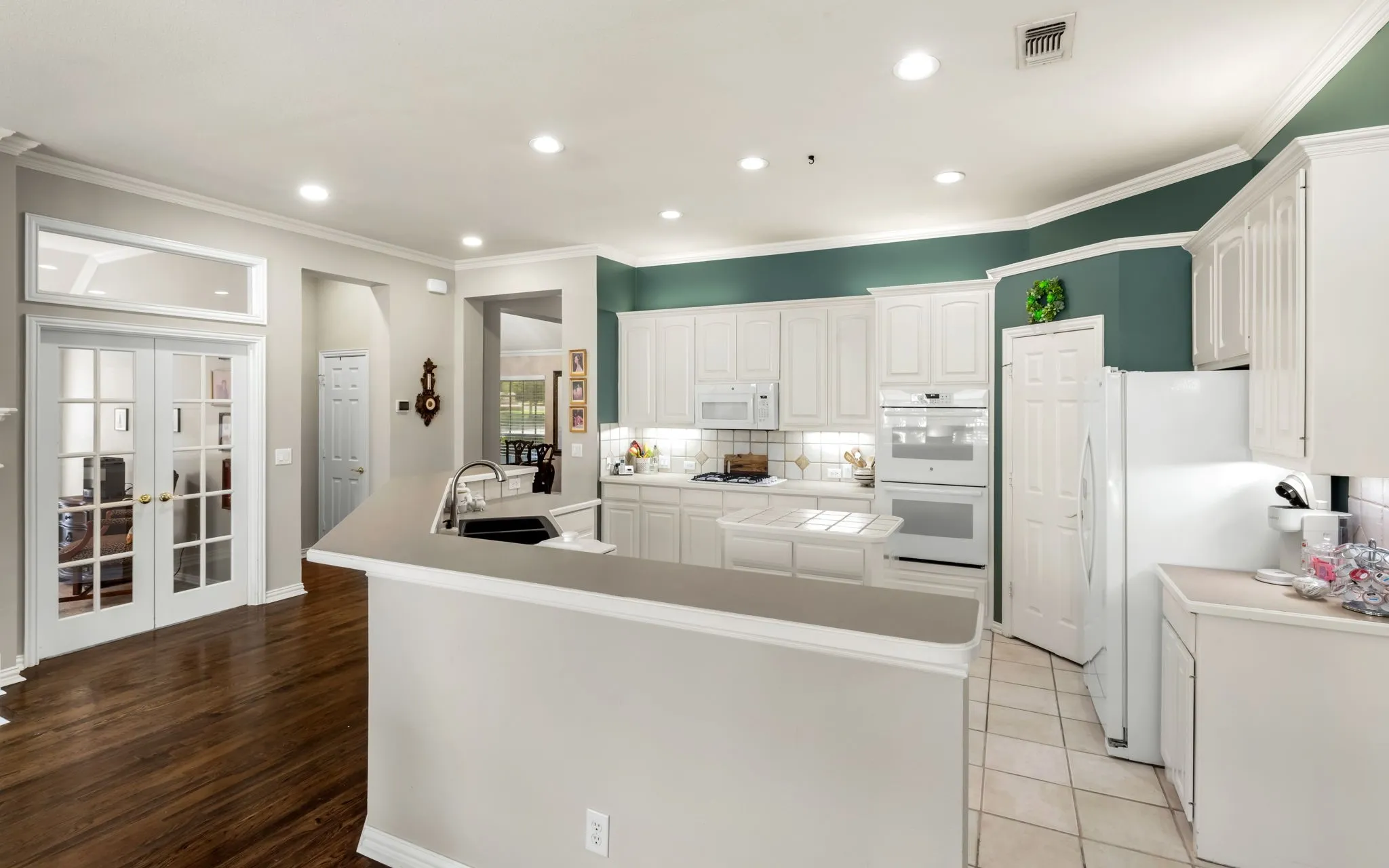 Kitchen featuring white cabinetry, built-in double ovens, a built-in microwave, a black undermount sink, and recessed lighting