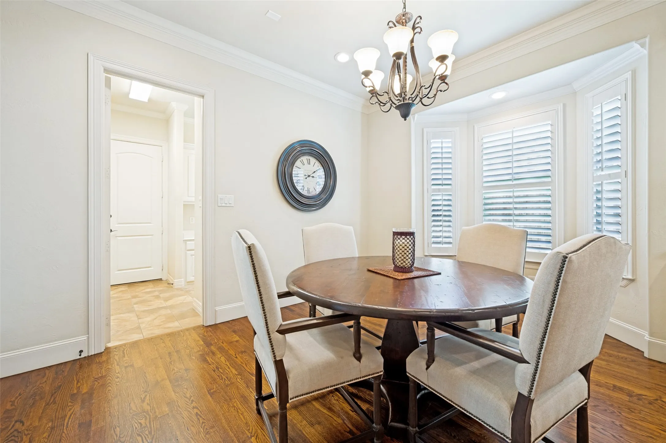 Dining area featuring wood-finish flooring, a decorative chandelier, and bay windows with plantation shutters