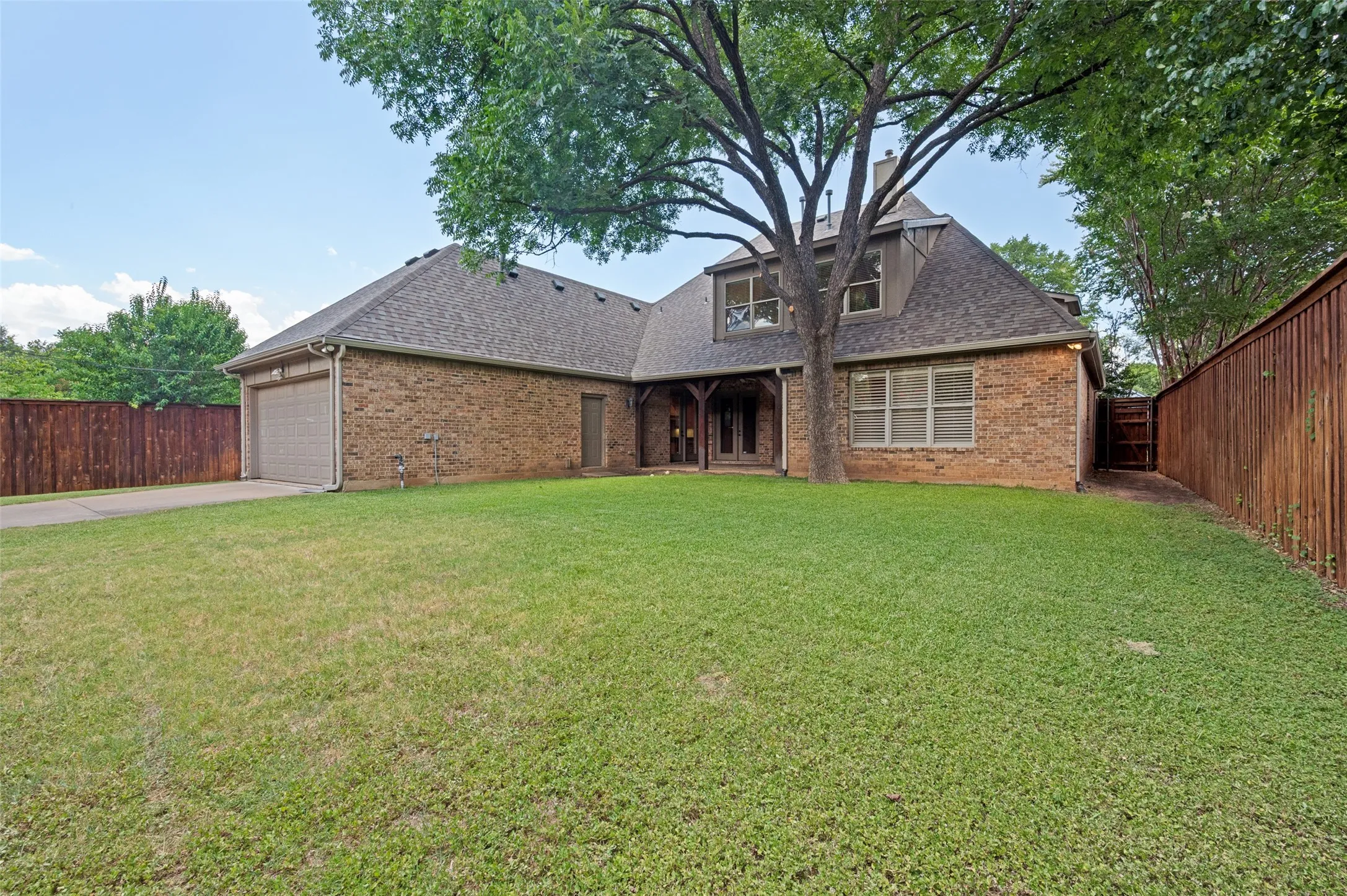 Brick exterior with a prominent mature tree, providing natural shade