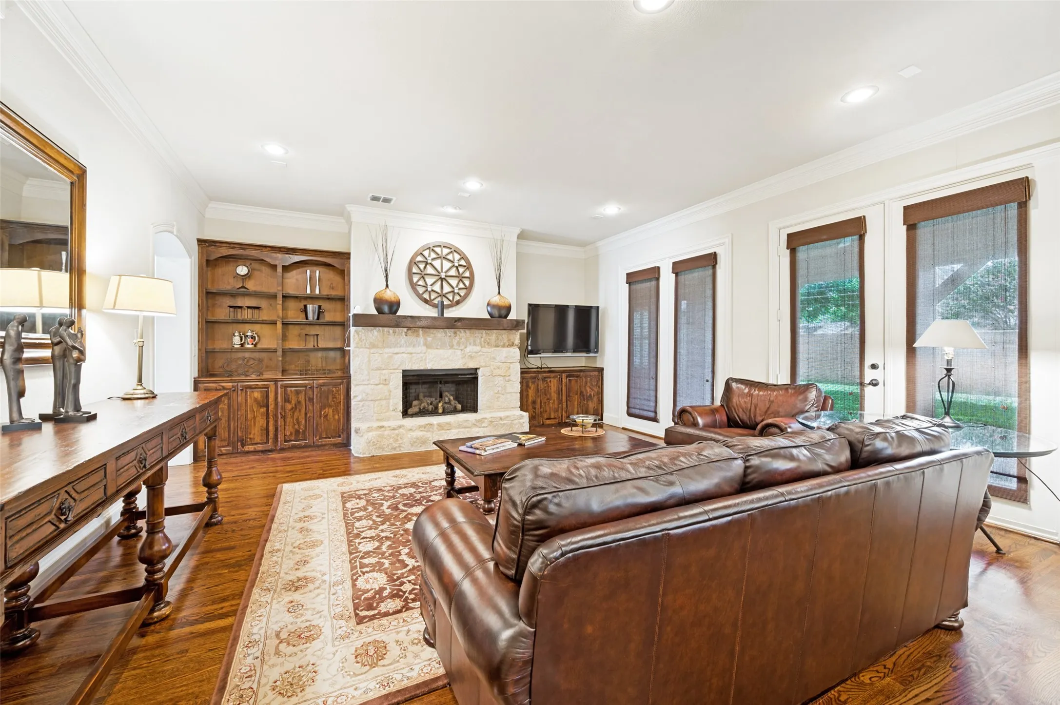 Living area featuring wood-finish flooring, a stone fireplace with a wood mantle, and built-in wood cabinetry