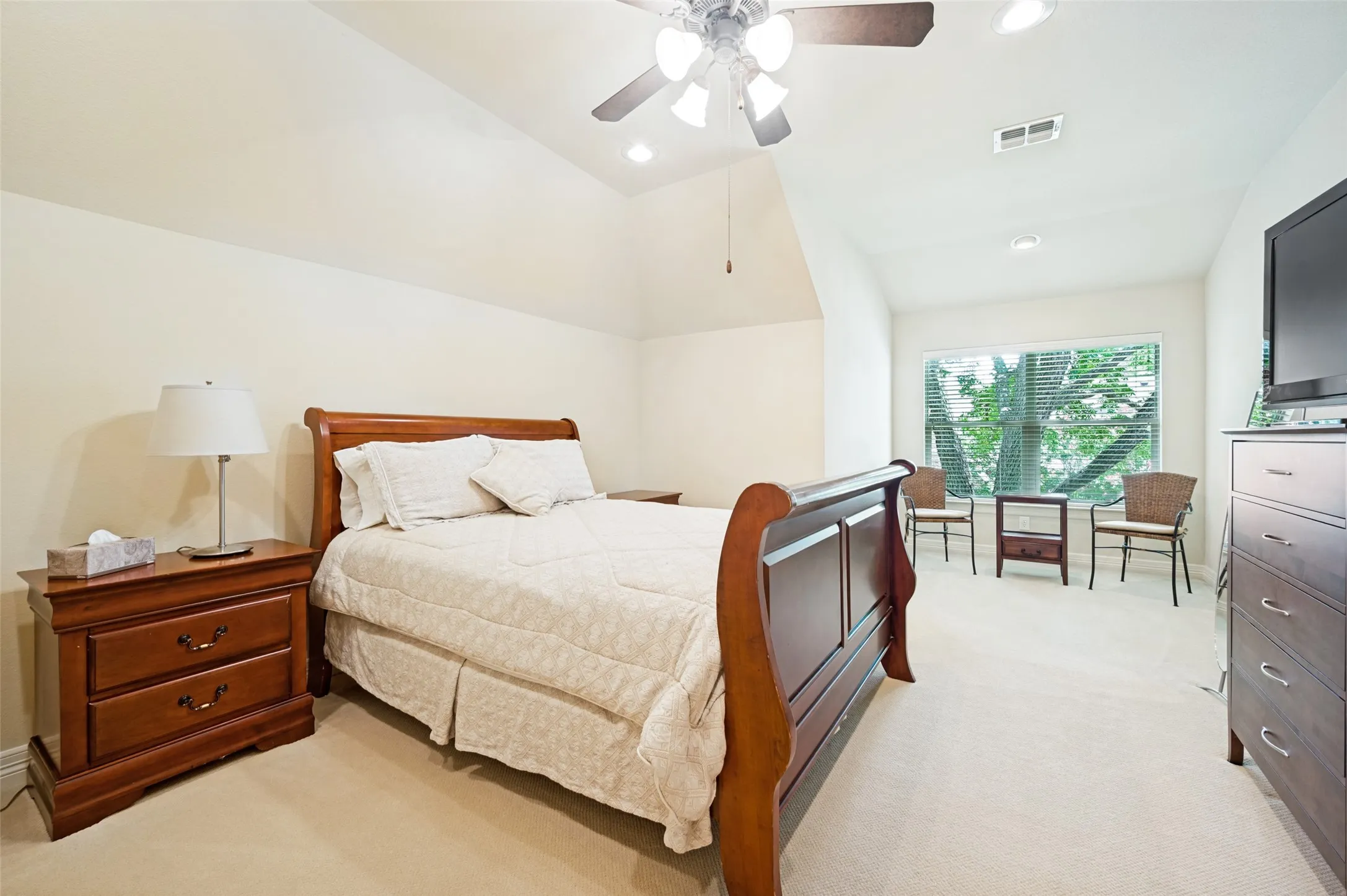 Spacious room featuring vaulted ceilings, recessed lighting, a ceiling fan with light, a large window with blinds, and light-colored carpeting