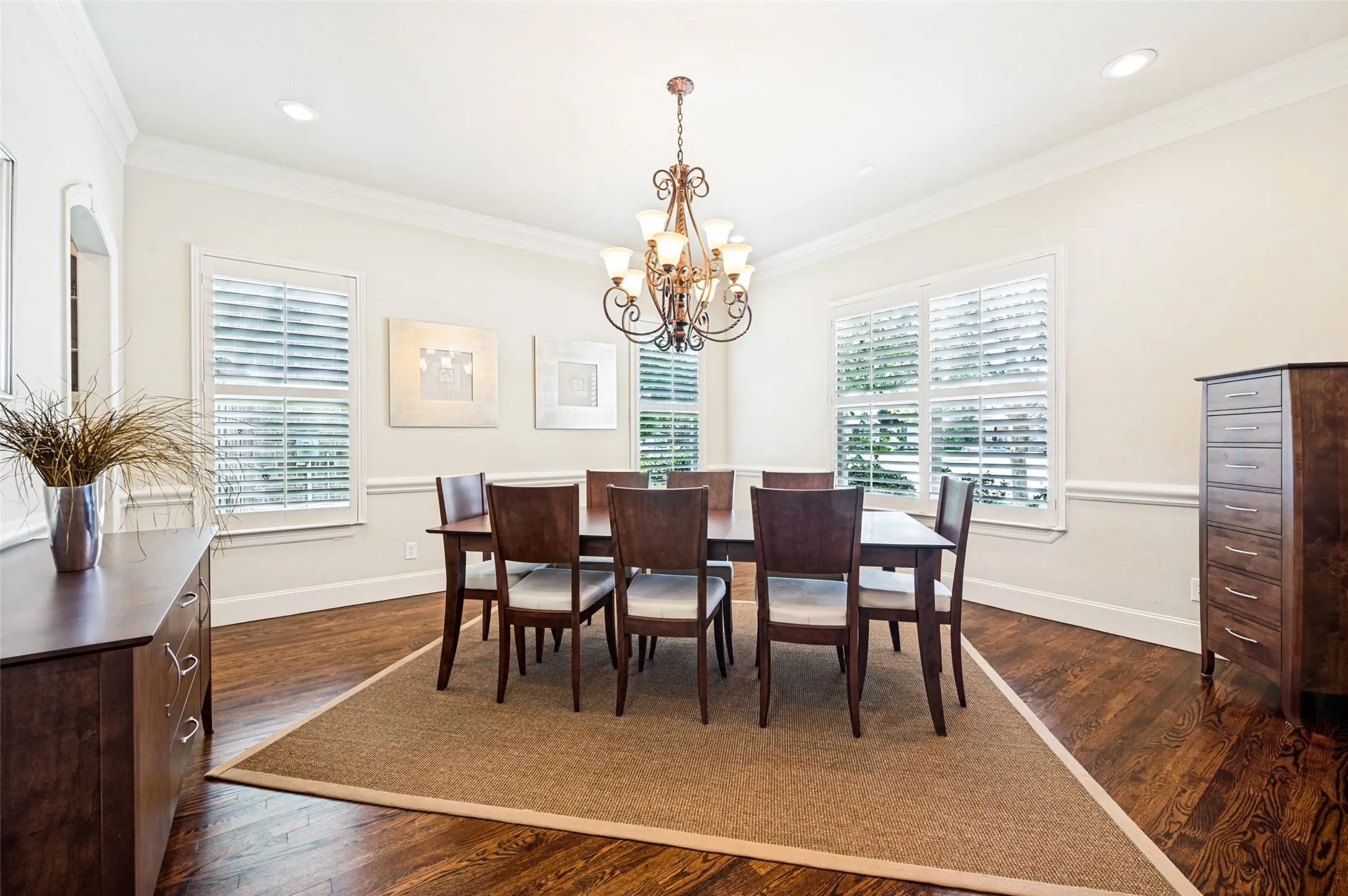 Formal dining area featuring hardwood flooring, crown molding, chair rail detailing, recessed lighting, and a decorative chandelier