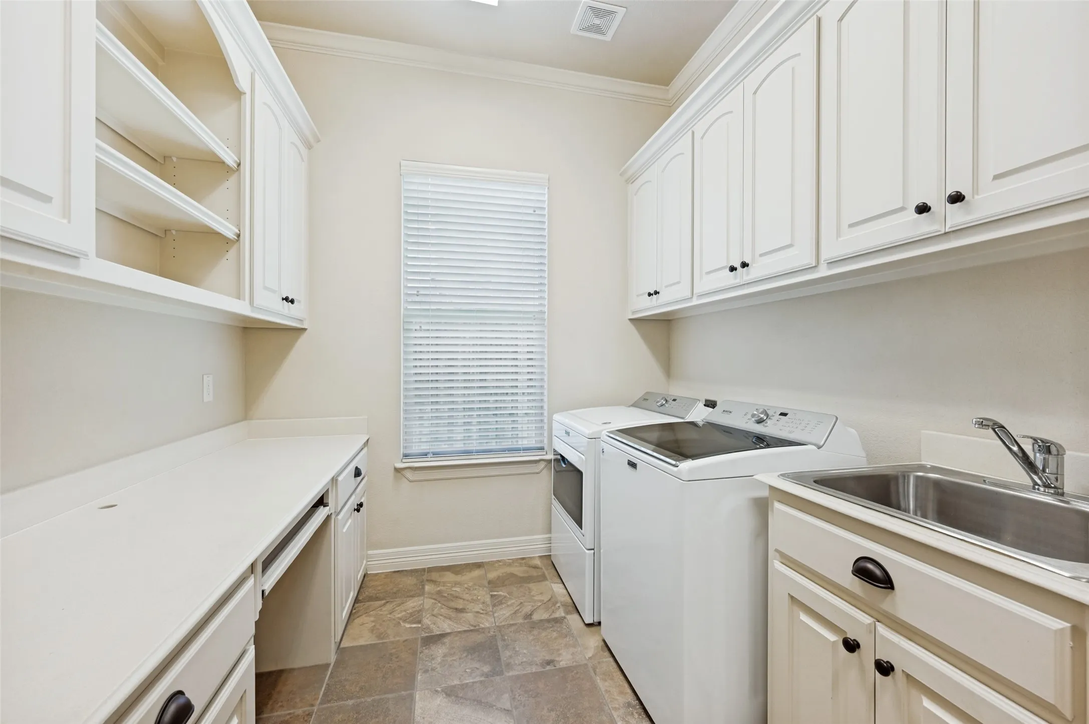 Dedicated utility room featuring extensive white cabinetry, durable countertop space, a built-in sink with faucet, and tile flooring