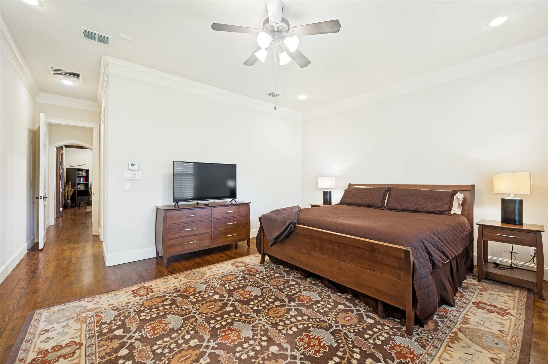Spacious room featuring wood-finish flooring, white crown molding, recessed lighting, and a ceiling fan