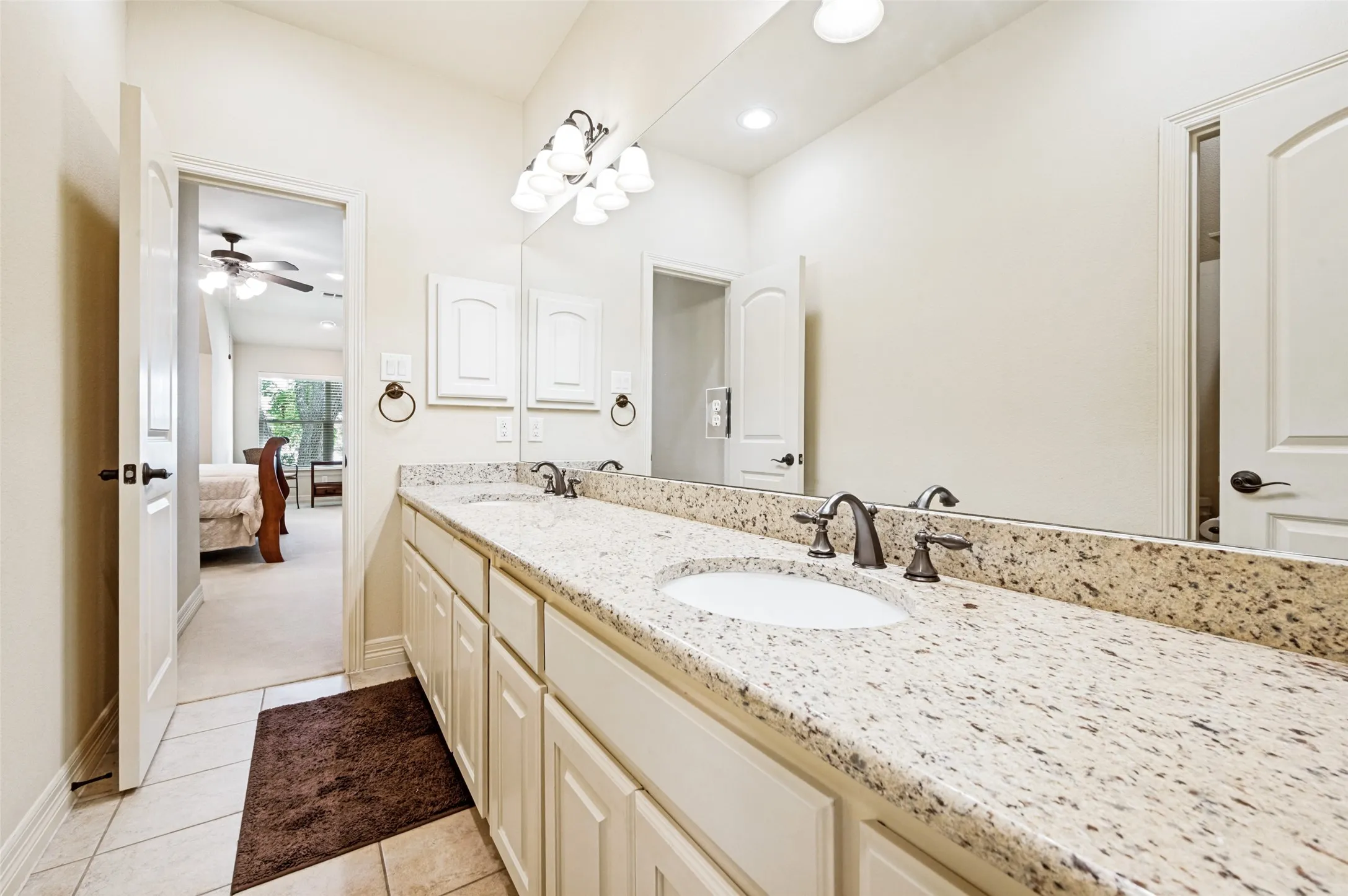 Bathroom vanity with dual undermount sinks, speckled countertop, and white cabinetry