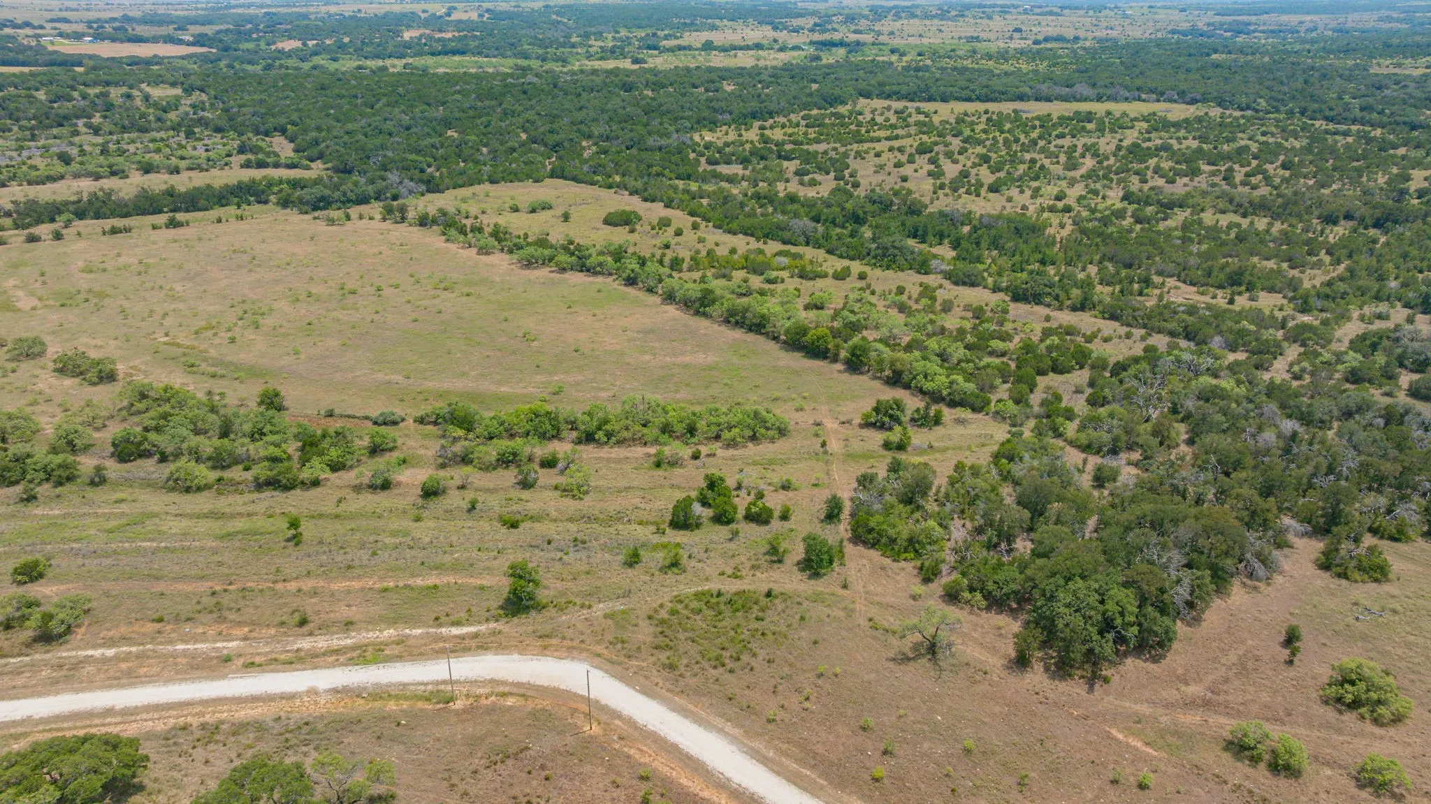 Expansive rural landscape featuring a winding gravel road and varied topography