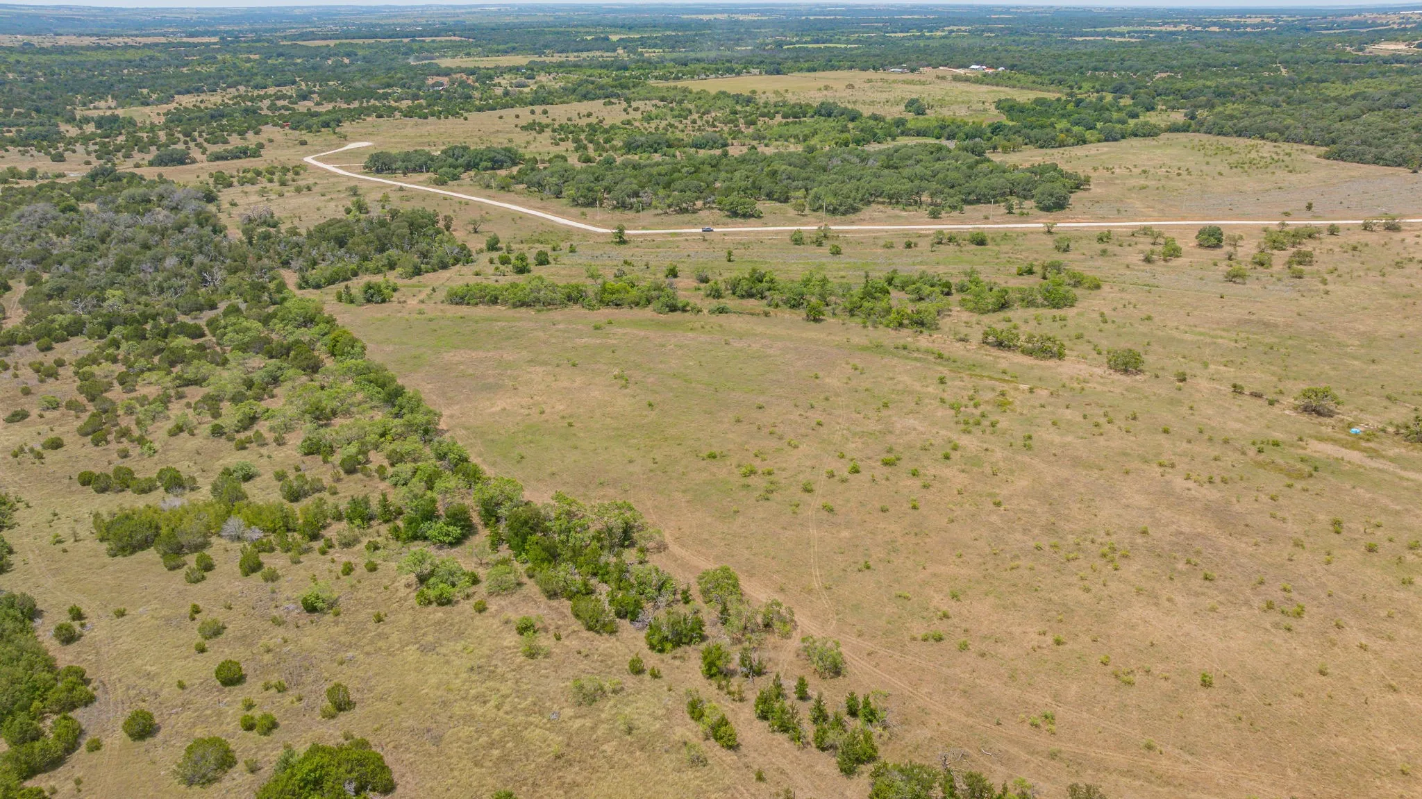 Expansive undeveloped land featuring a combination of open fields and natural tree clusters