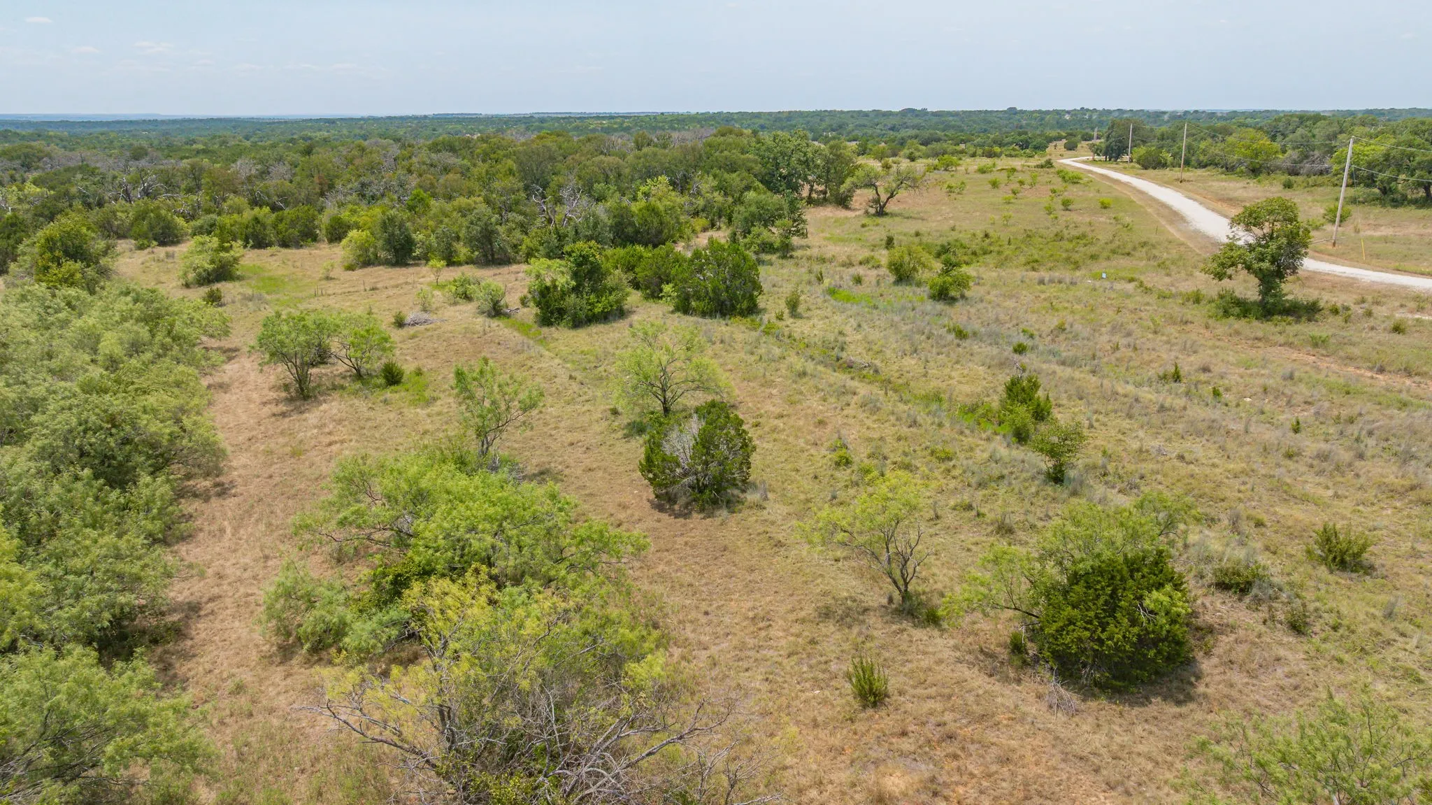 Expansive rural acreage featuring scattered native vegetation and mature trees across open pastureland