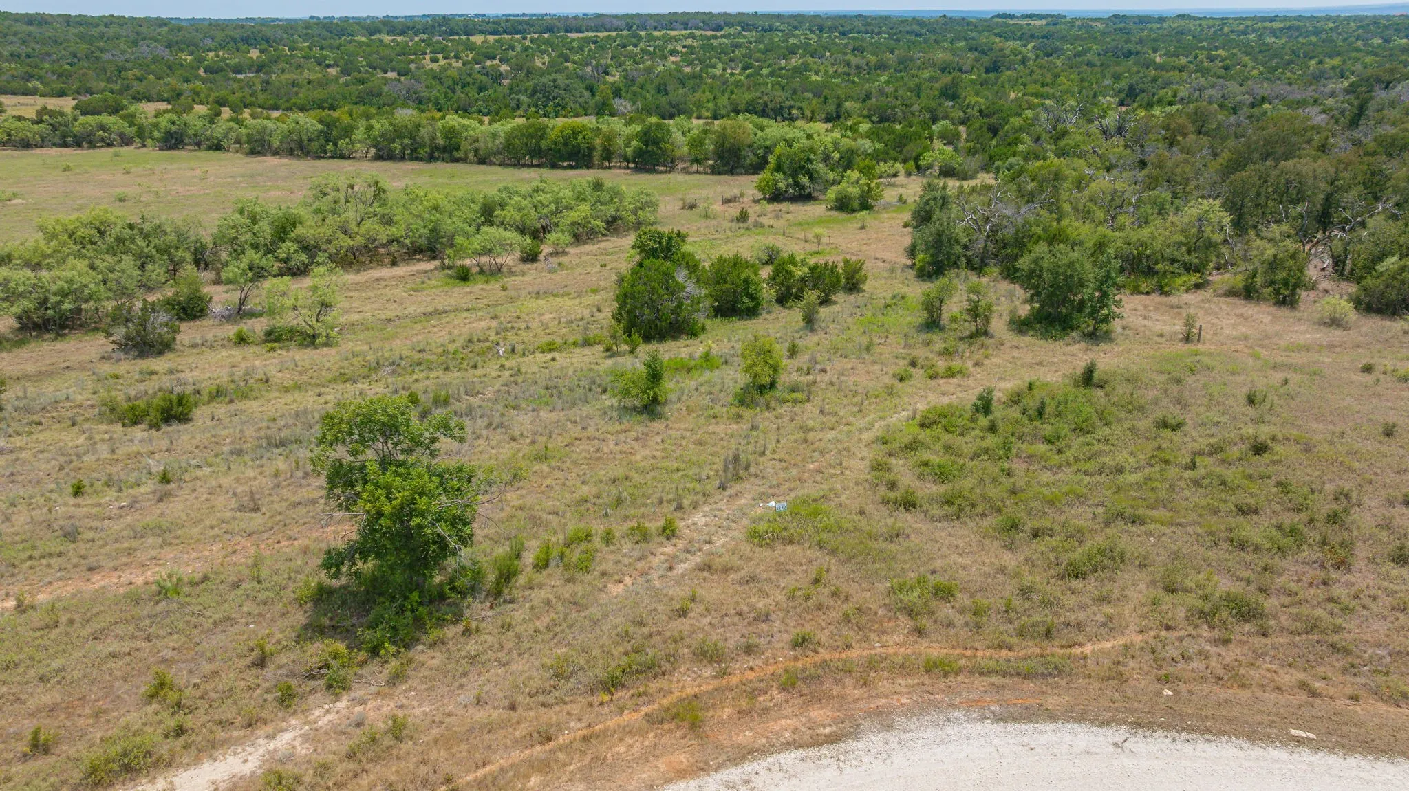 Expansive rural acreage featuring open pastureland with scattered mature trees and natural vegetation