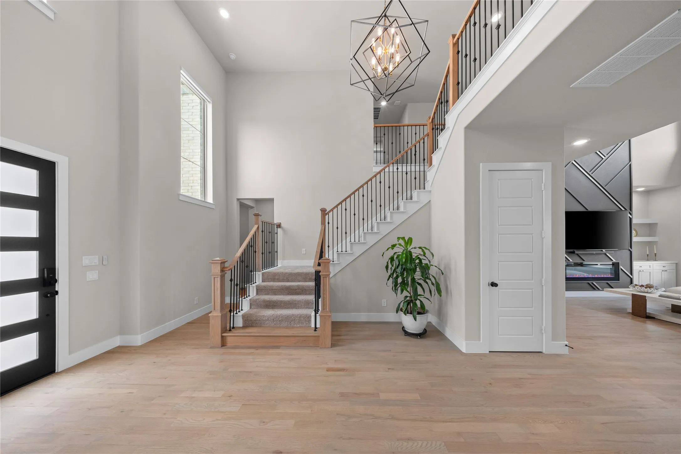 Bright two-story foyer with soaring ceilings, hardwood flooring, and abundant natural light from multiple windows