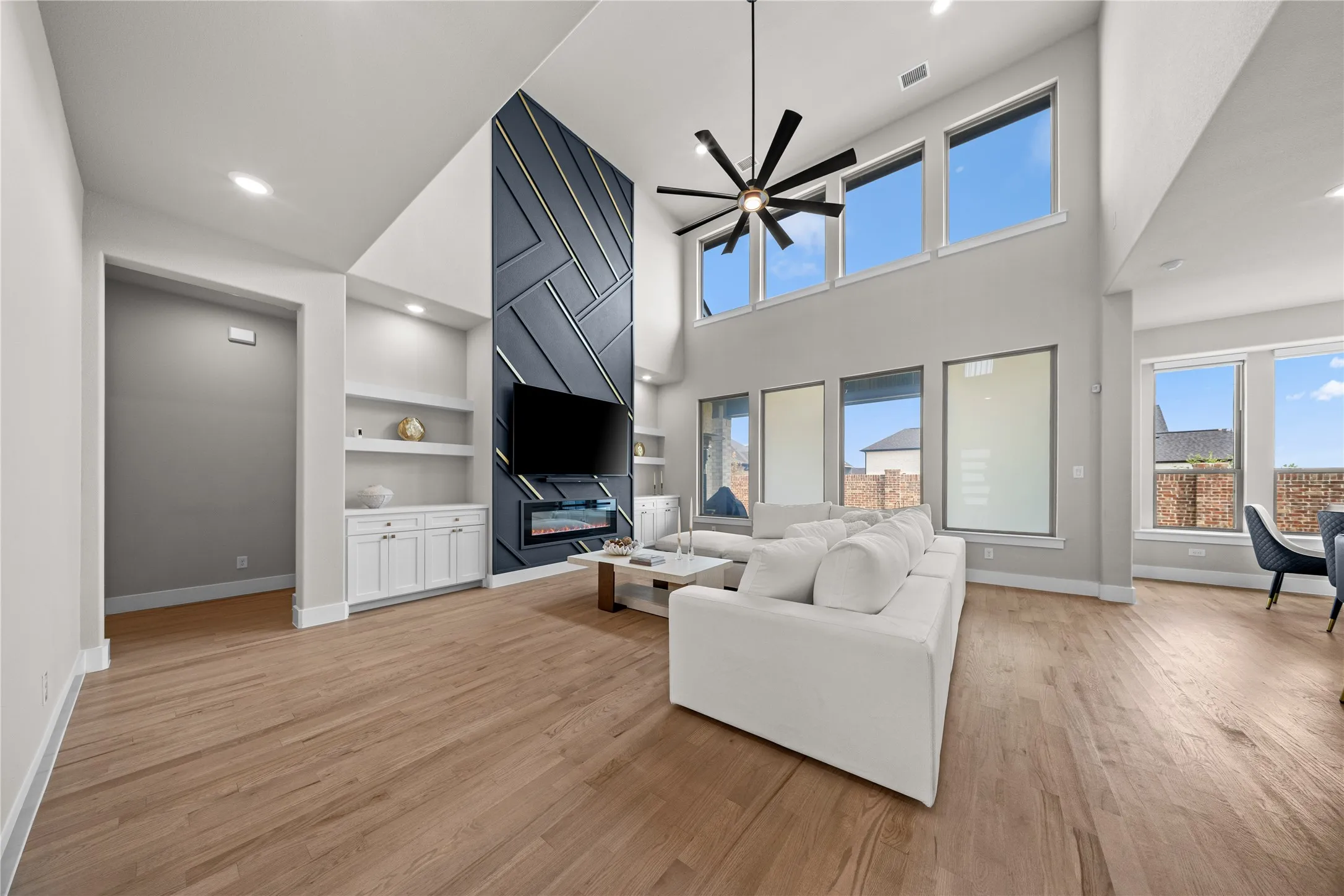 Two-story living area with wood-finish flooring, a contemporary fireplace, and a striking accent wall