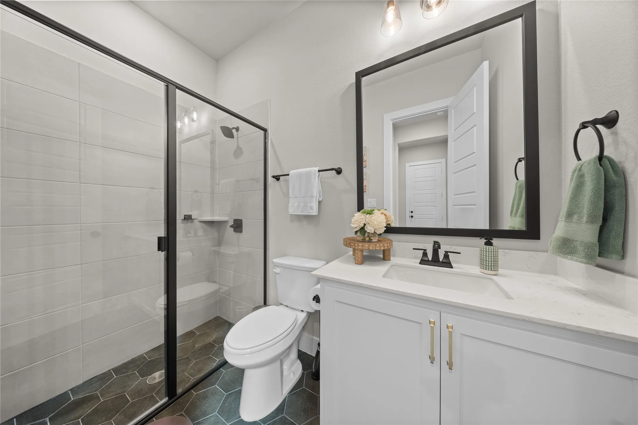 Contemporary bathroom featuring a floating white vanity with dual handles, quartz countertop, and matte black faucet