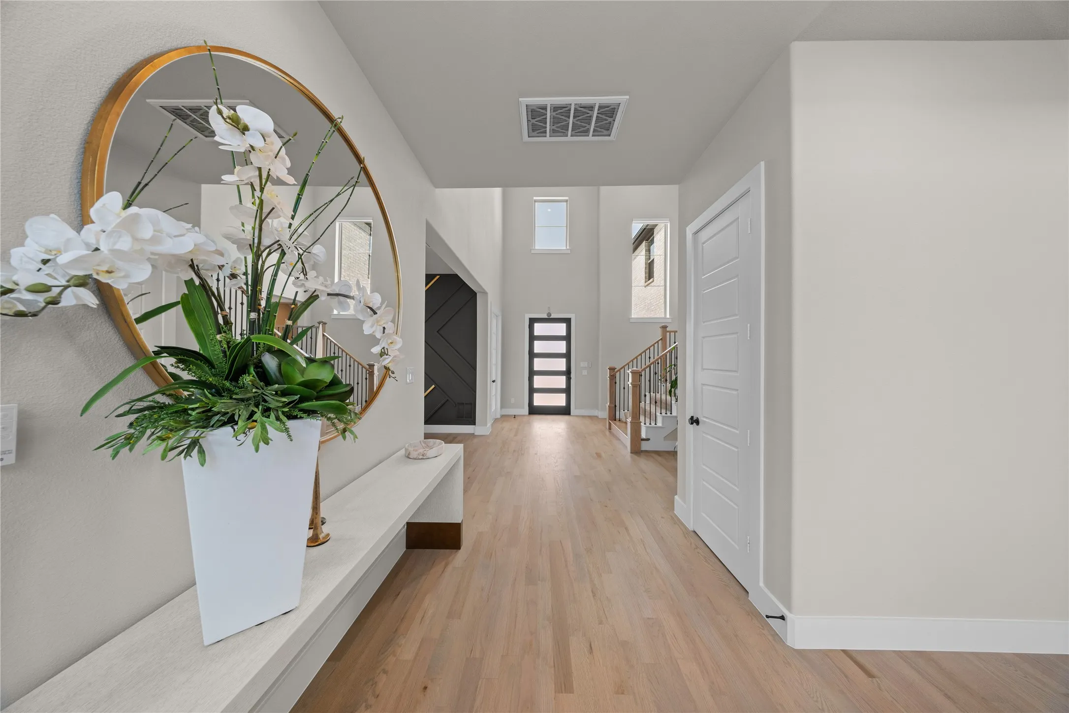 Wood-finish flooring, white paneled doors, and a two-story entry with an abundance of natural light