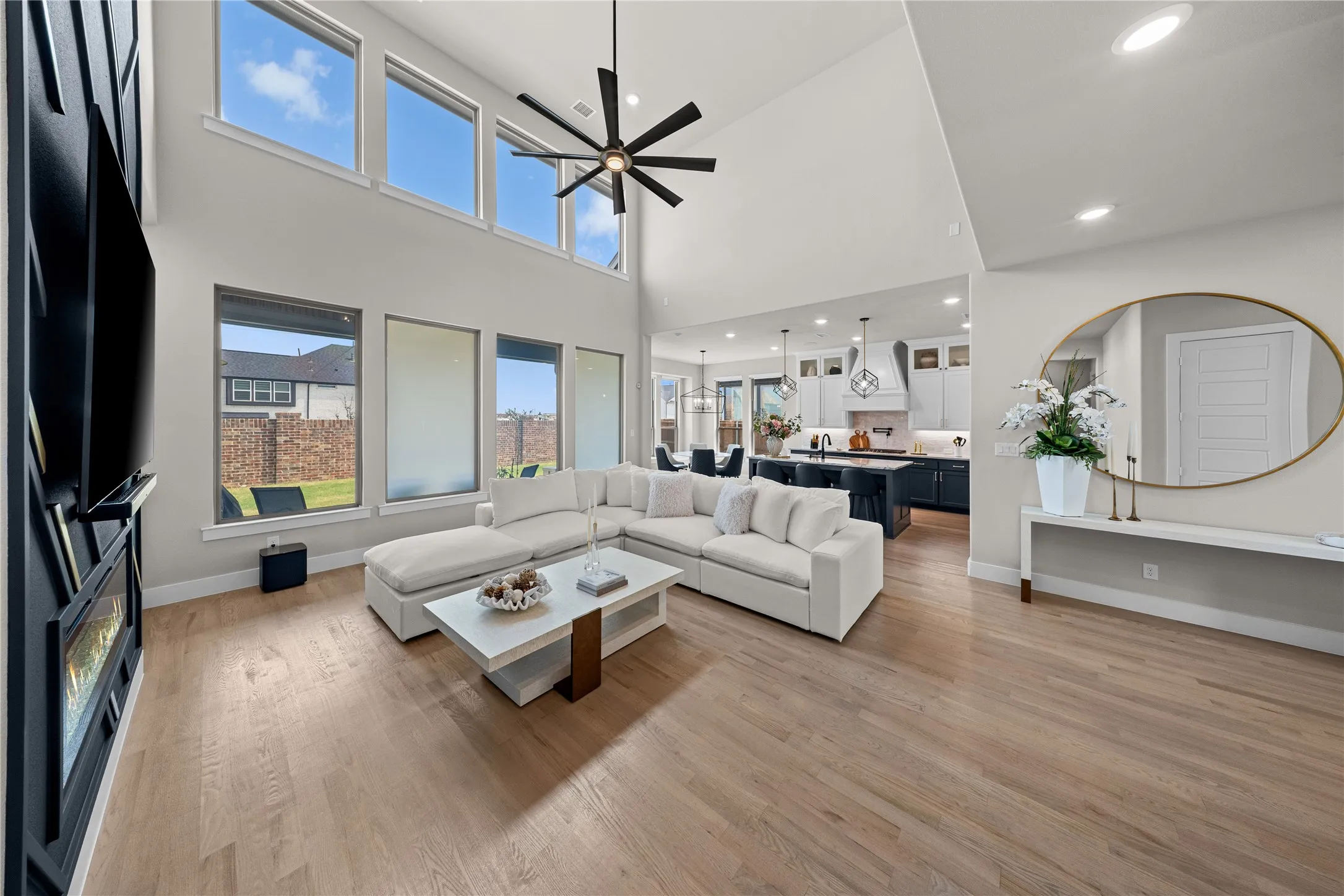 Vaulted ceiling with a contemporary ceiling fan, light wood-finish flooring, and a built-in electric fireplace