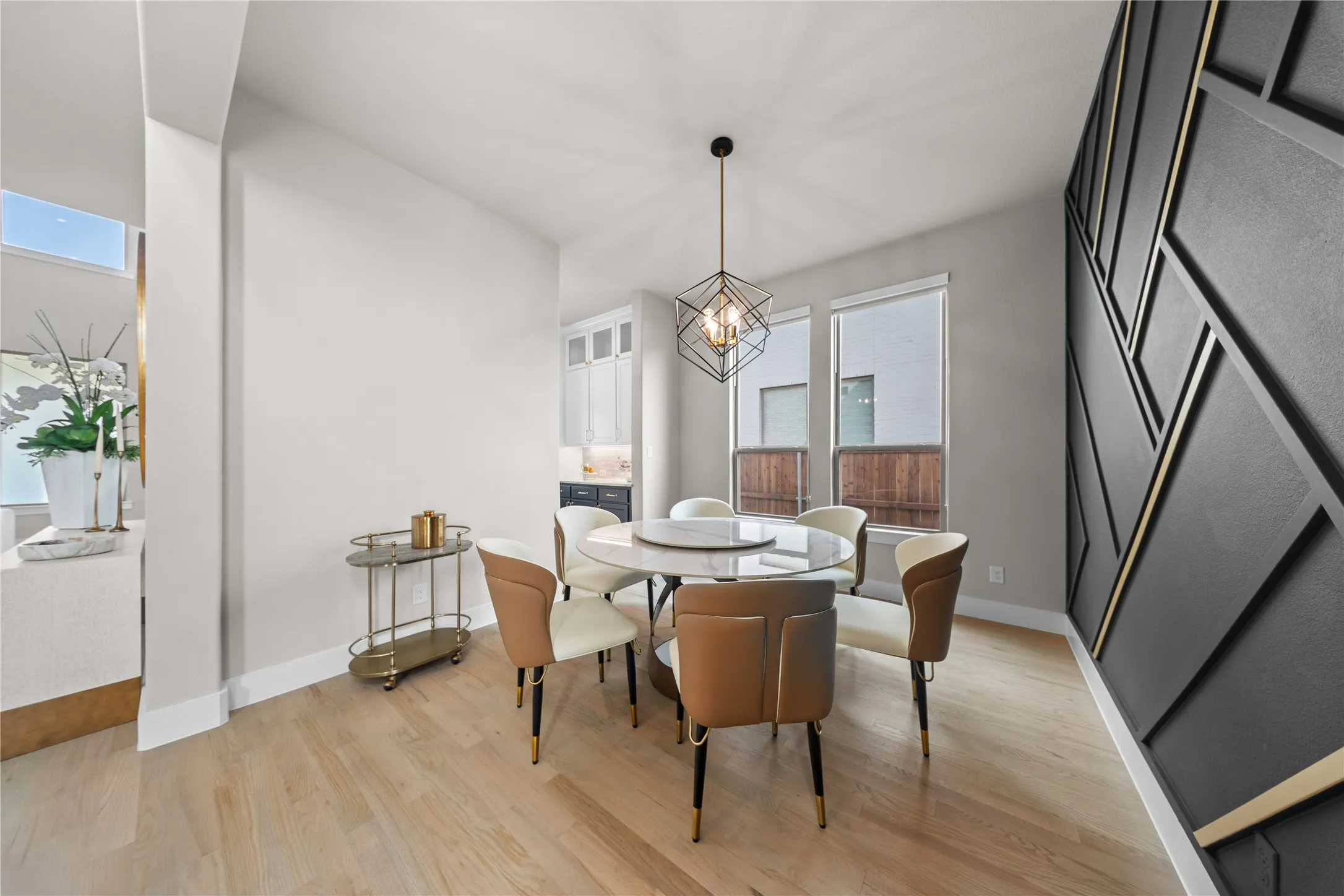 Light wood-finish flooring with a decorative accent wall featuring geometric paneling and metallic accents