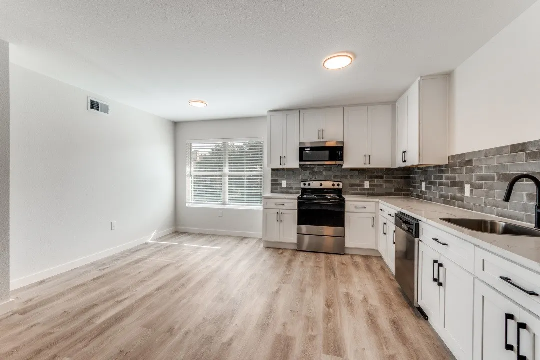 Modern kitchen featuring white cabinetry, light countertops, a dark subway tile backsplash, and wood-finish flooring