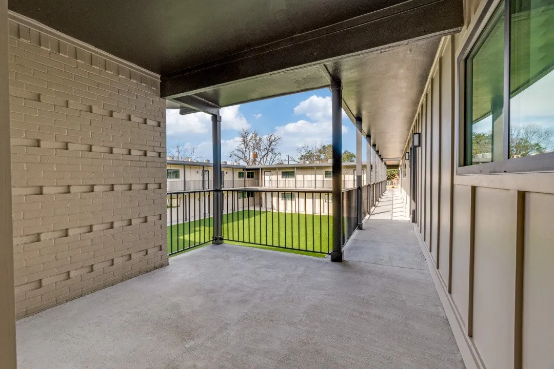 Covered balcony featuring concrete flooring and black metal railing