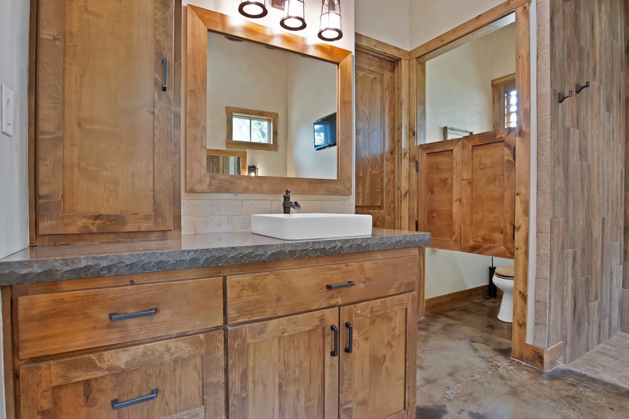 Bathroom vanity featuring a stone-finish countertop with a vessel sink and oil-rubbed bronze faucet