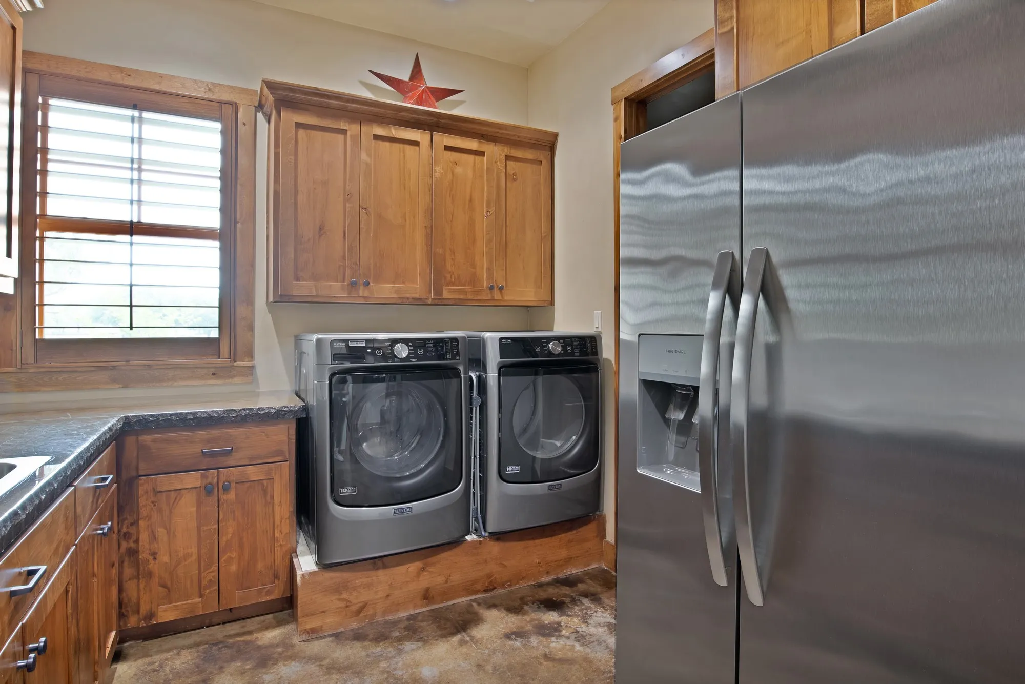 Spacious utility area featuring wood-finish cabinetry, a large stainless steel refrigerator, and a built-in countertop with integrated sink