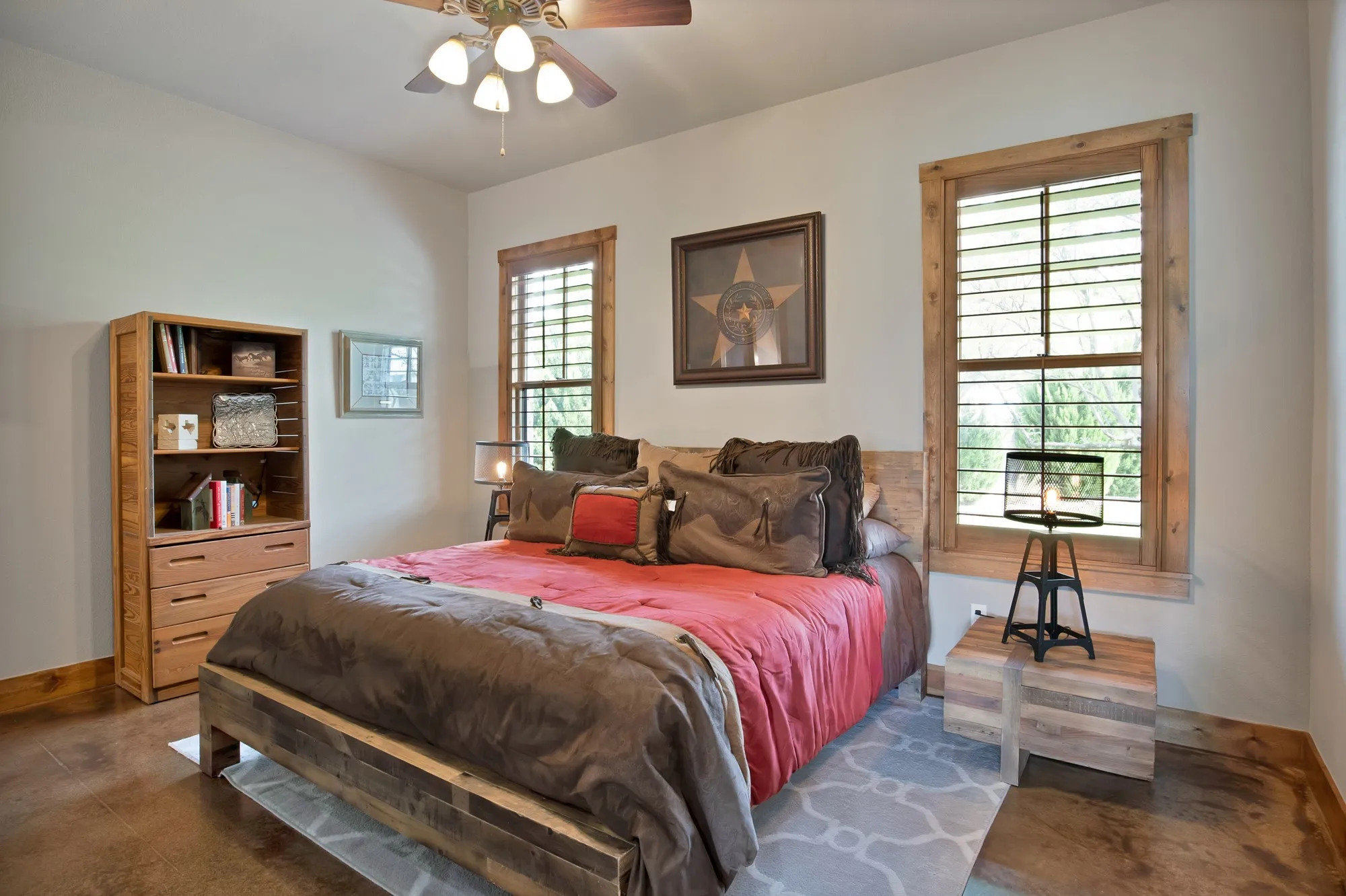 Spacious room featuring two windows with wooden plantation shutters and trim, a five-blade ceiling fan with integrated lighting, and stained concrete flooring