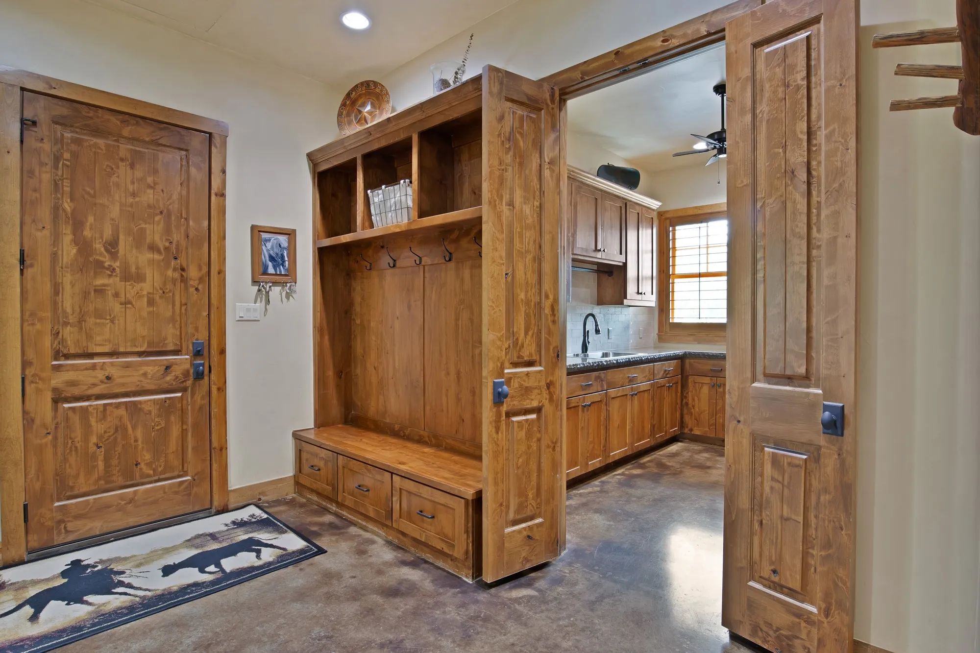 Utility area featuring a built-in wooden hall tree with storage, a solid wood entry door, and concrete flooring