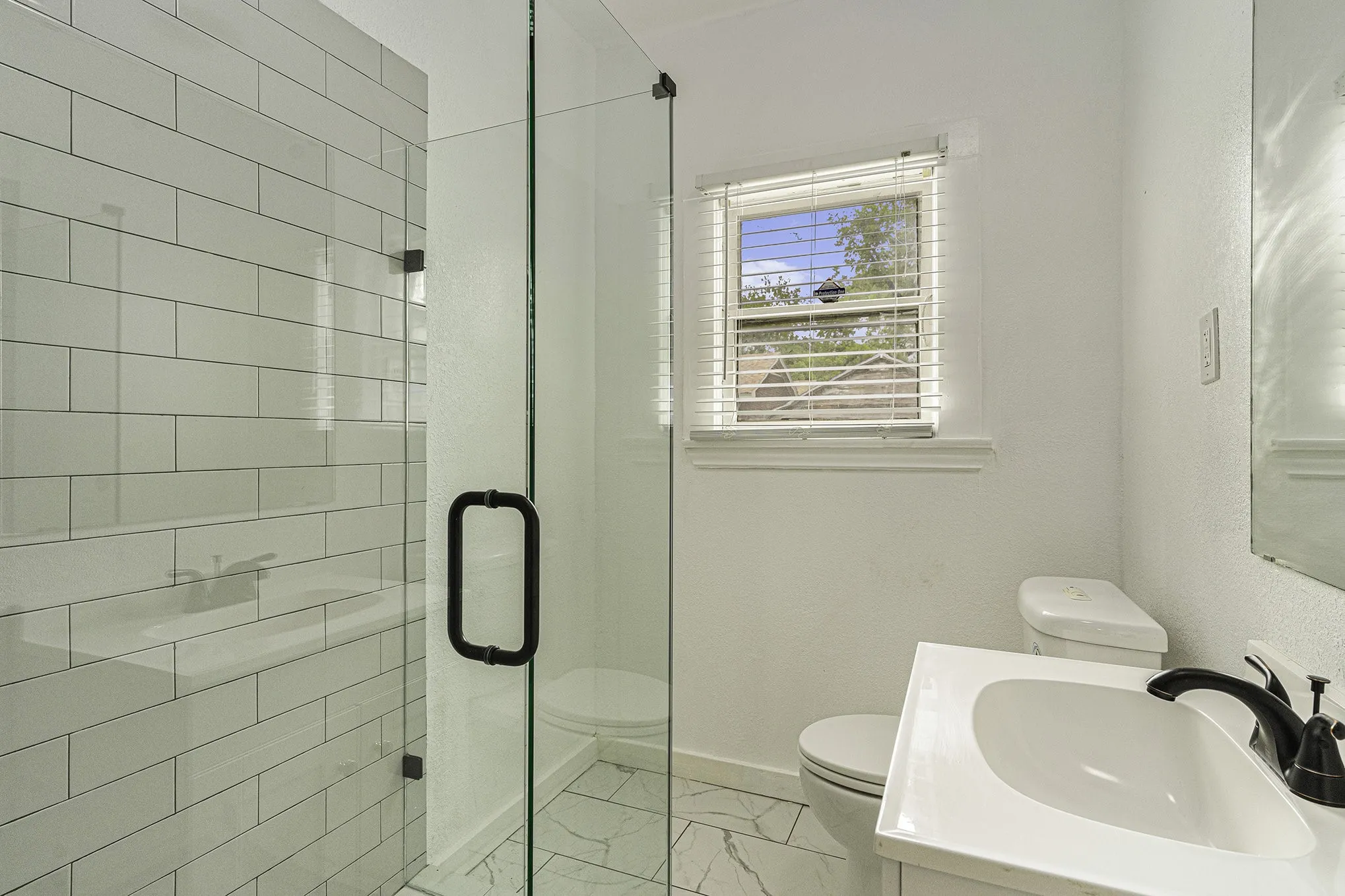 Bathroom featuring a shower with shower door, tile patterned floors, toilet, and vanity