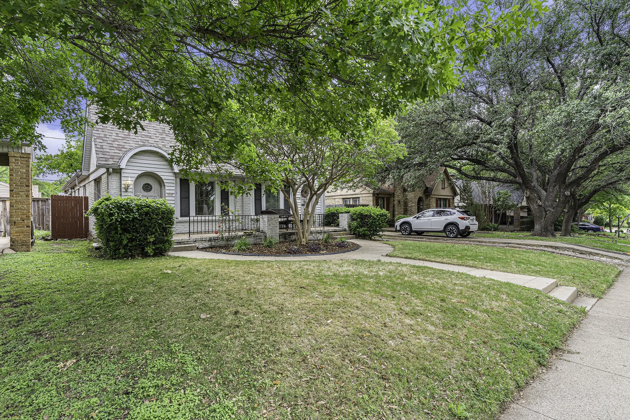View of property hidden behind natural elements featuring a front lawn