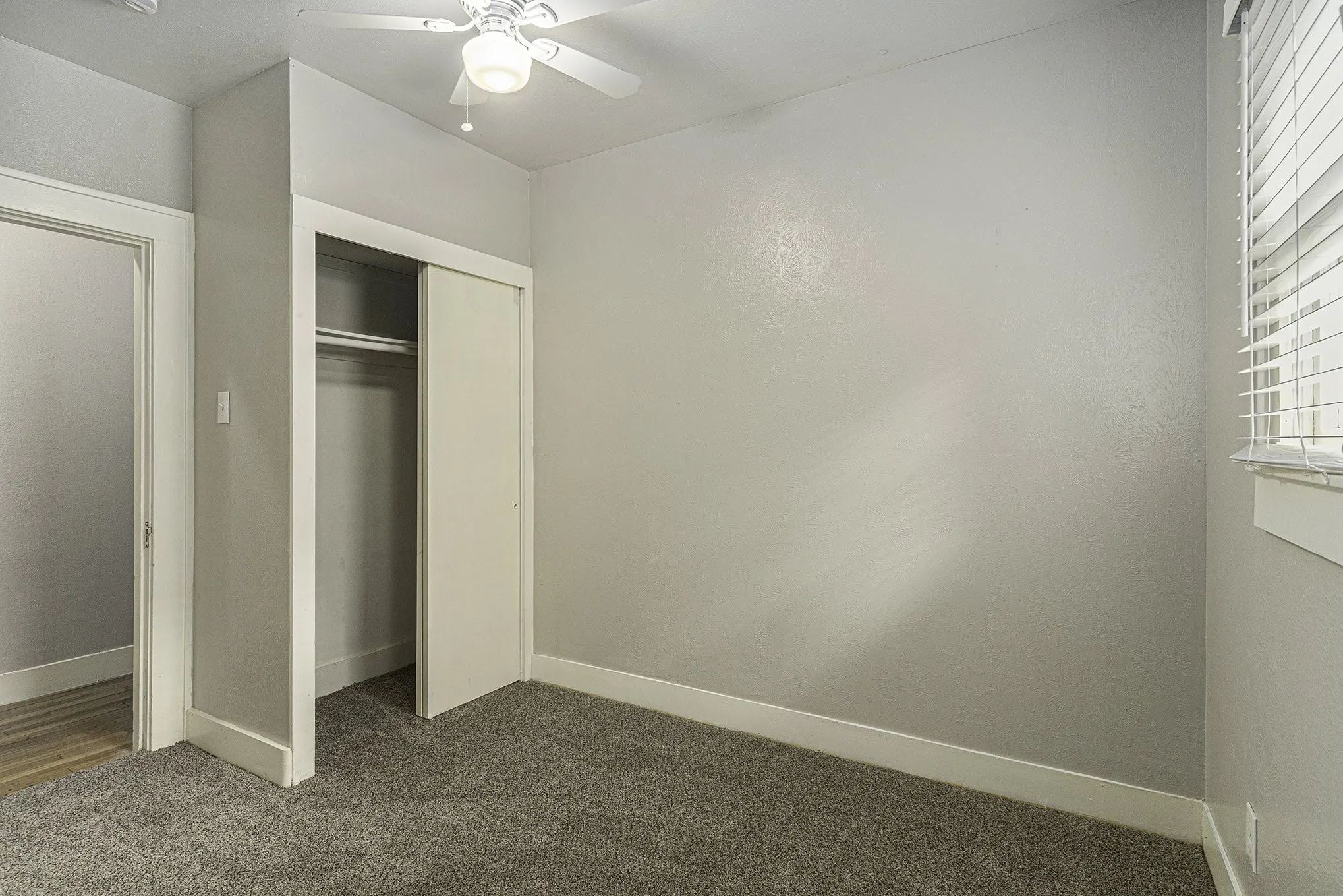 Unfurnished bedroom featuring dark carpet, ceiling fan, and a closet
