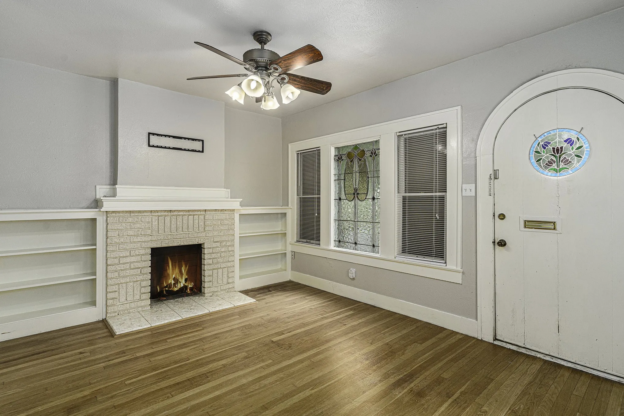Unfurnished living room with hardwood / wood-style flooring, a fireplace, and ceiling fan