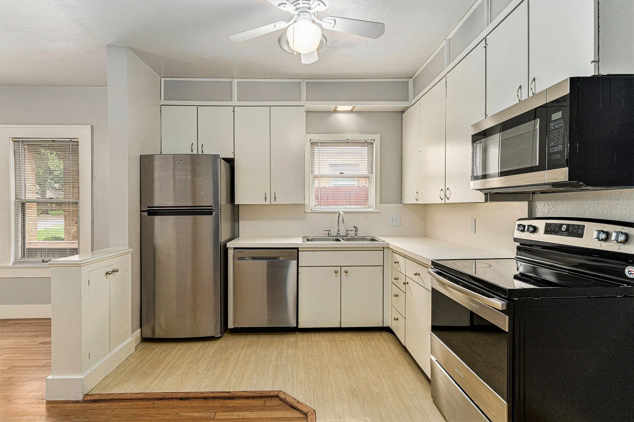 Kitchen with white cabinetry, light hardwood / wood-style flooring, ceiling fan, stainless steel appliances, and sink