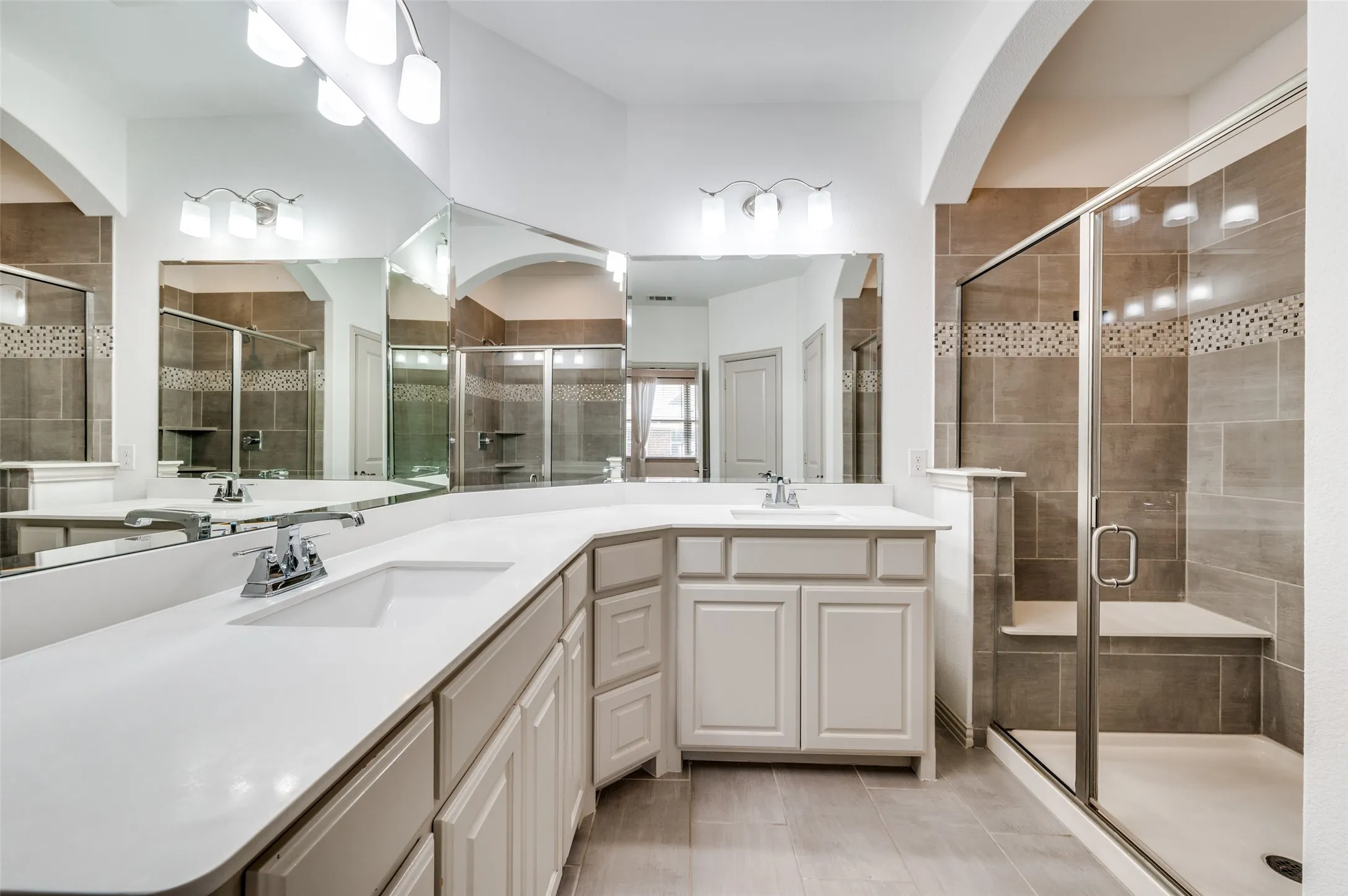 Bathroom with double vanity, large mirror, and stall shower, offering a spacious primary or secondary bath setup with extra counter space and storage, appealing to buyers who want a McKinney Texas townhouse with updated bathrooms, double sinks, and convenient layout in a well located Collin County community