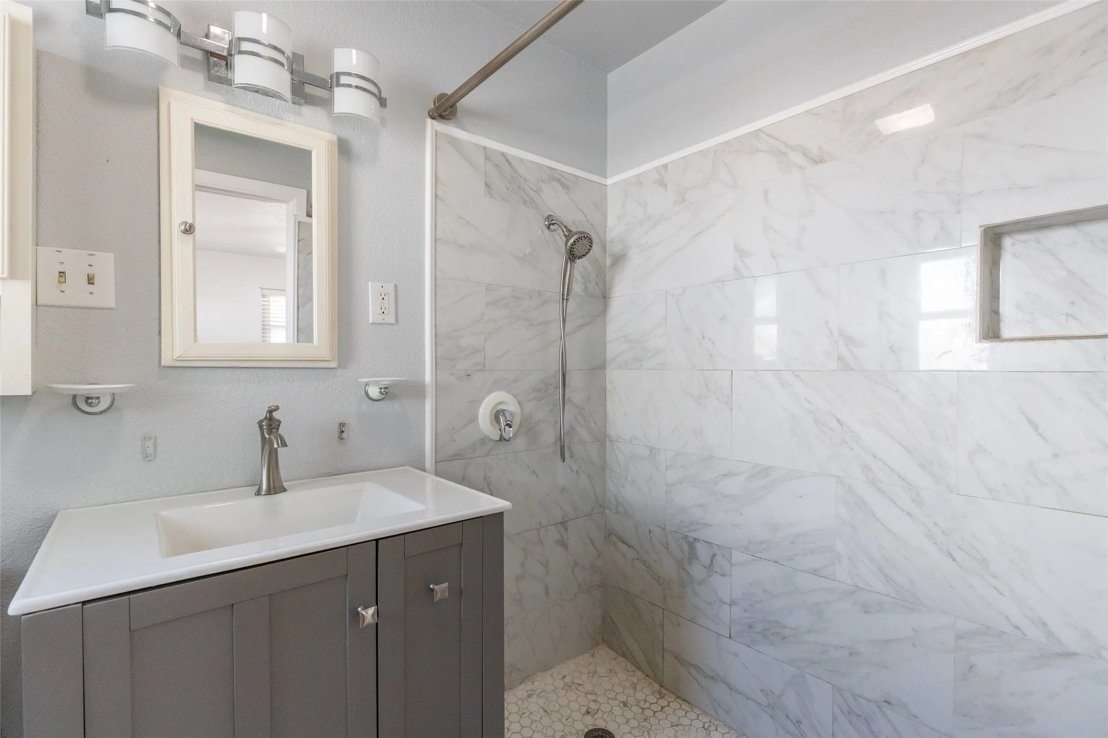 Bathroom featuring a gray vanity with an integrated white sink, brushed nickel faucet, and coordinating hardware