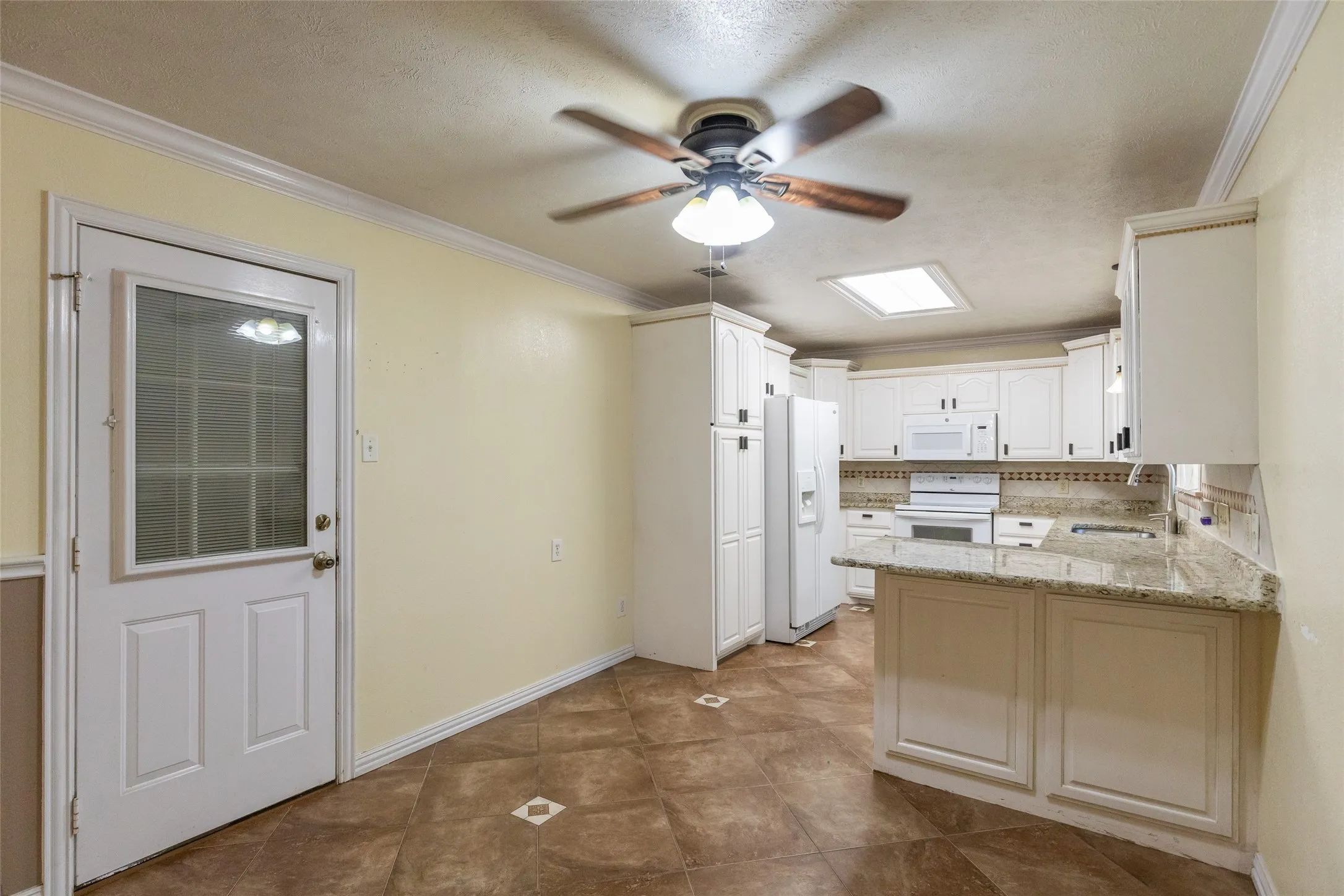 Spacious kitchen featuring white cabinetry, light-toned countertops, and a full suite of white appliances