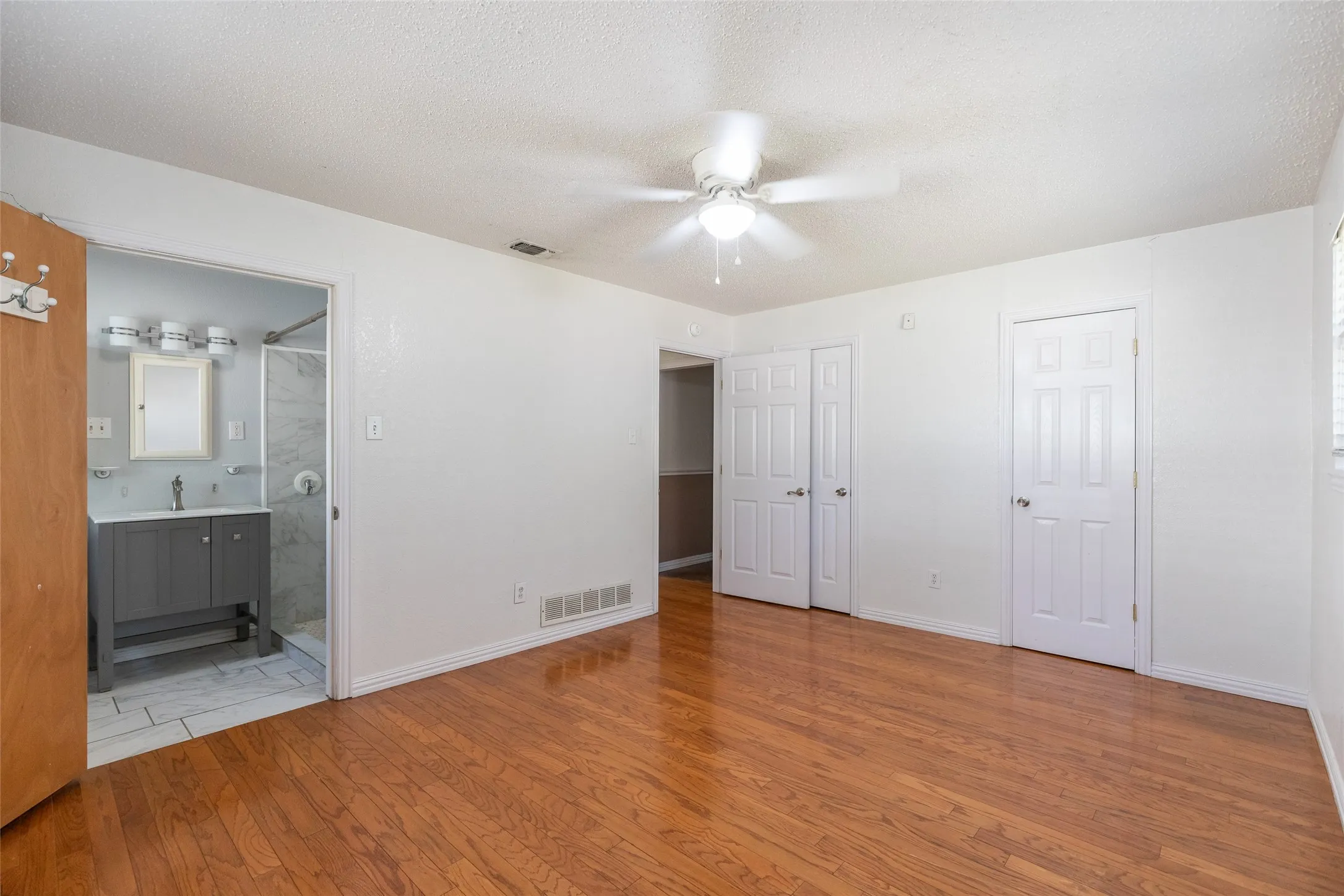 Bedroom with wood-finish flooring, a ceiling fan, and white walls